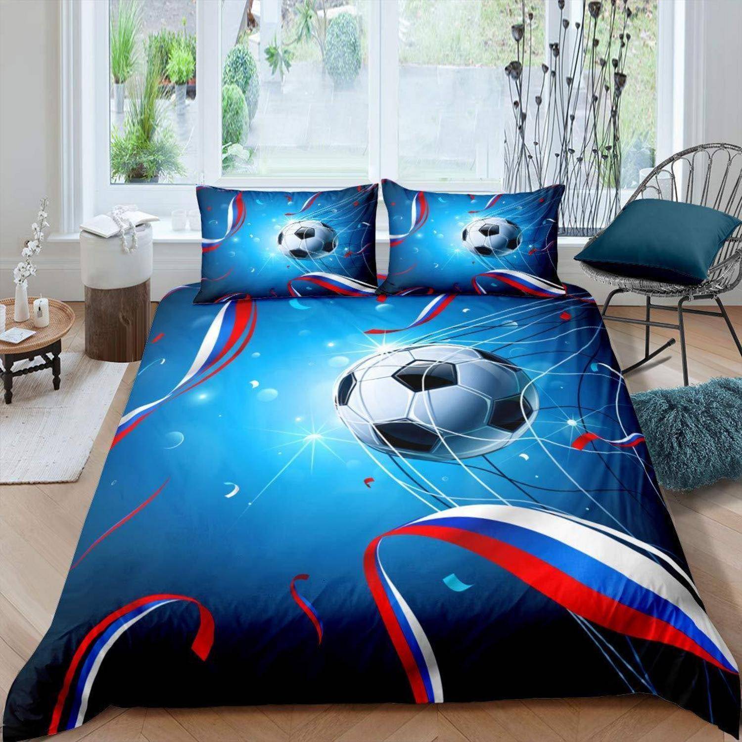 Blaues fußballthematisches Bett mit Ball und rot-weißen Streifen auf der Bettdecke und Kissen in einem hellen modernen Schlafzimmer