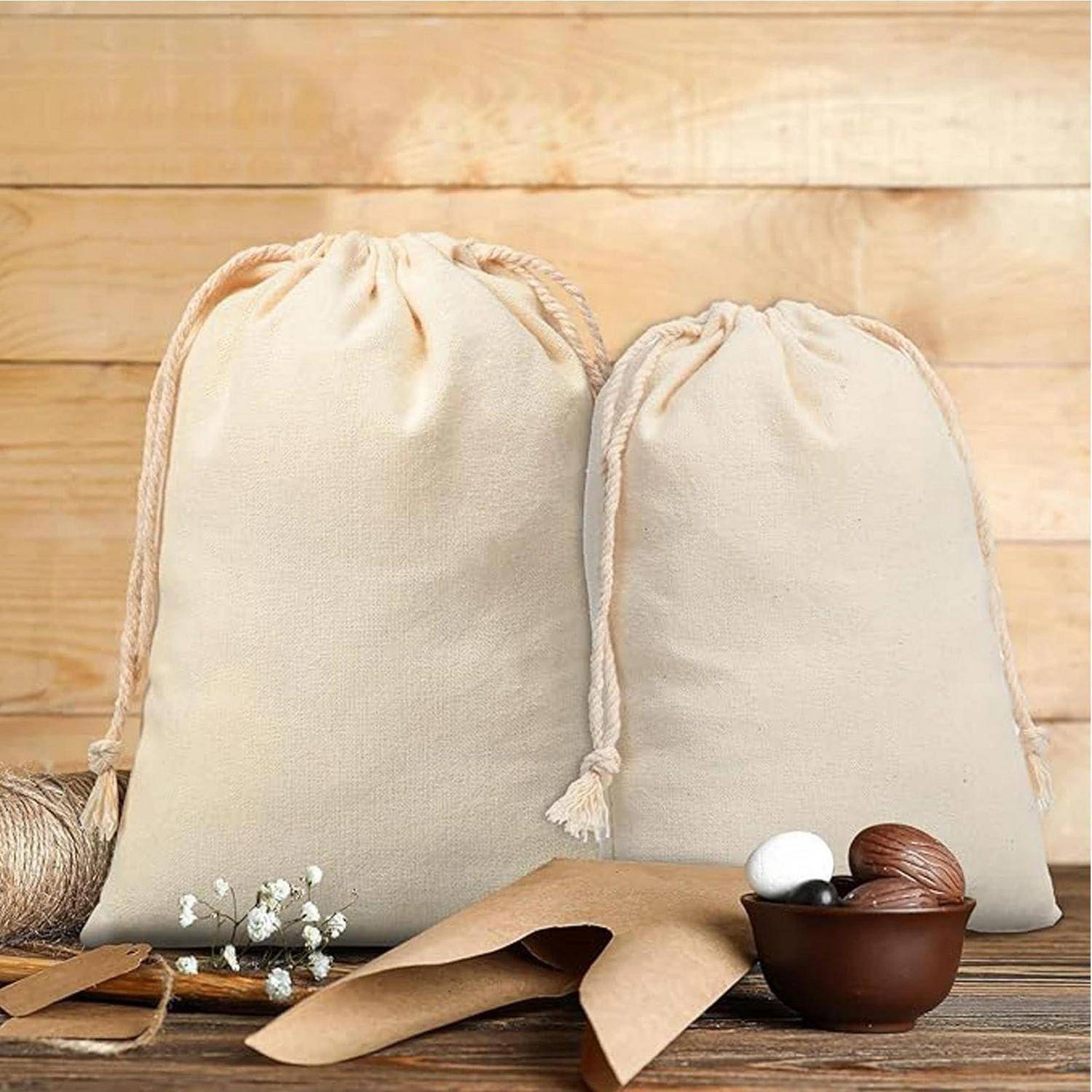Zwei beige Baumwollbeutel mit Kordelzug auf einem Holztisch, mit brauner Papierverpackung und einer kleinen Schüssel mit weißen und dunklen Eiern davor.