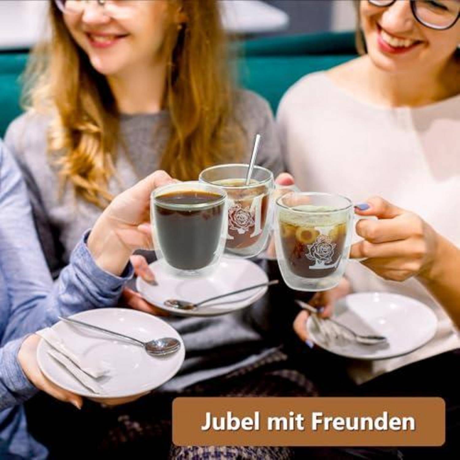 Zwei lächelnde Freunde stoßen mit Bechern heißer Getränke an, während sie kleine Teller halten; der Text lautet „Jubel mit Freunden".