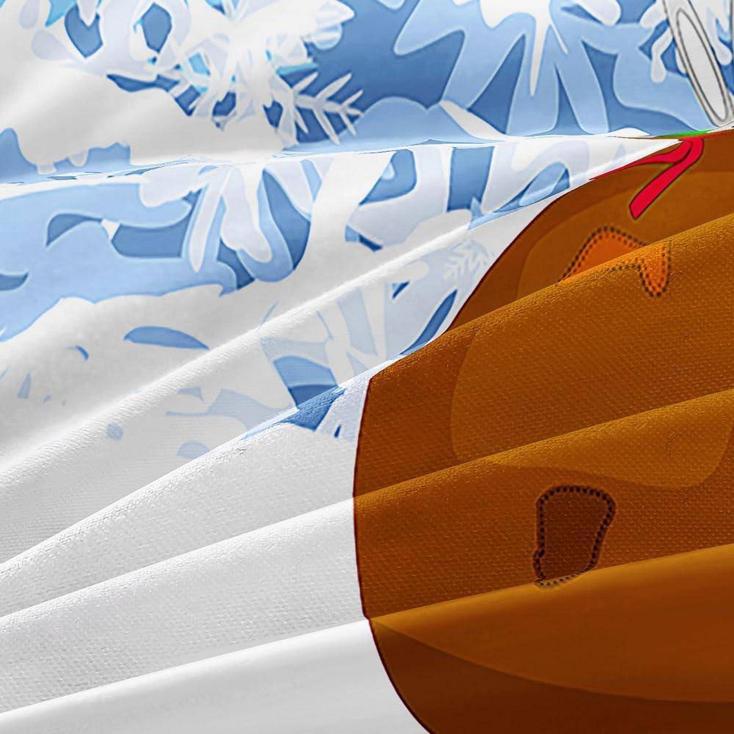 Nahaufnahme eines gefalteten blau-weiß gemusterten Stoffes mit Schneeflocken-Muster neben einer braunen Bärenkopf-Grafik auf orangefarbenem Material.