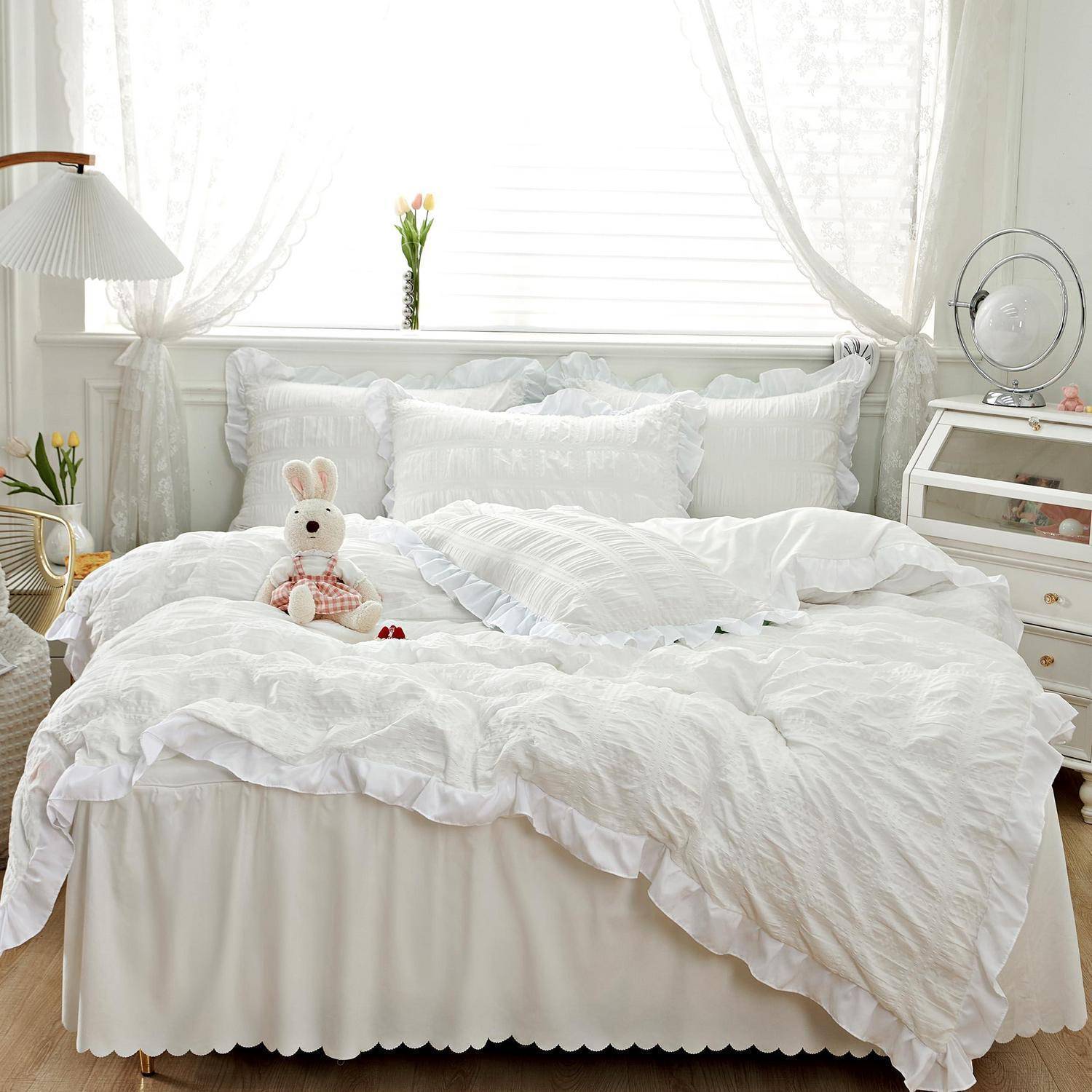 Helles weißes Schlafzimmer mit einem ordentlich gemachten Bett, weichem Hasenstofftier, Nachttischlampe und kleiner Kommode neben einem sonnendurchfluteten Fenster.