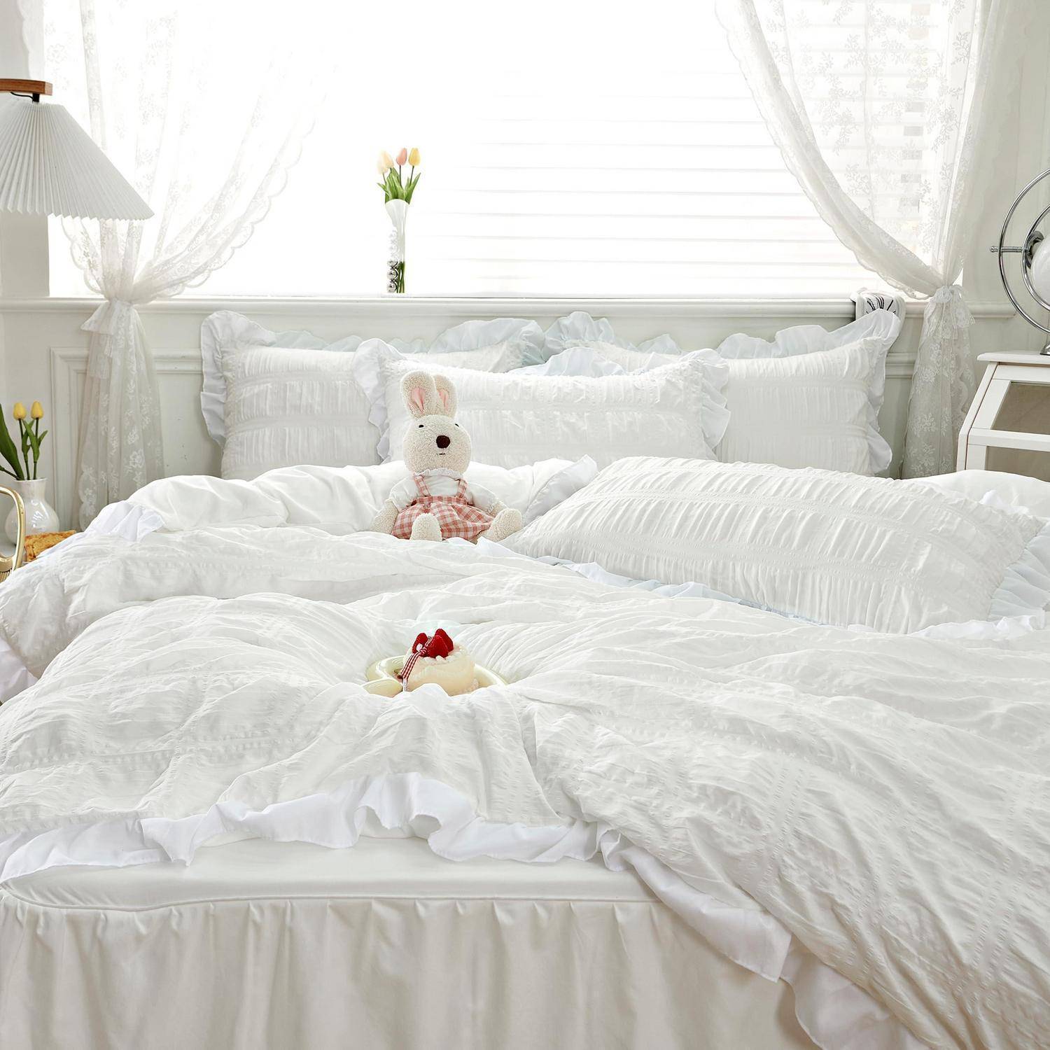 Ein hell leuchtendes, ordentlich gemachtes Bett mit flauschiger Bettwäsche, einem kleinen Kuschelhase und einem gefalteten Handtuch auf der Daunendecke in einem weichen, luftigen Schlafzimmer.