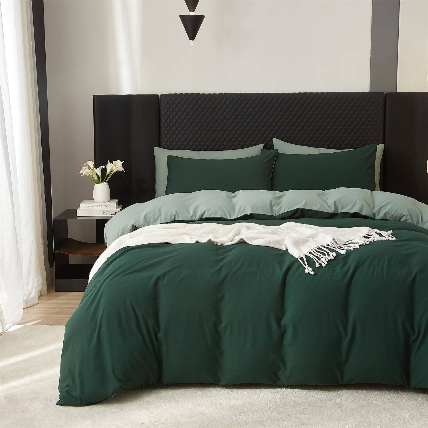 Ein ordentlich gemachtes Bett mit dunkelgrüner Bettwäsche und Kissen, einem schwarz gepolsterten Kopfteil und einem Nachttisch mit Blumen in einem modernen Schlafzimmer.