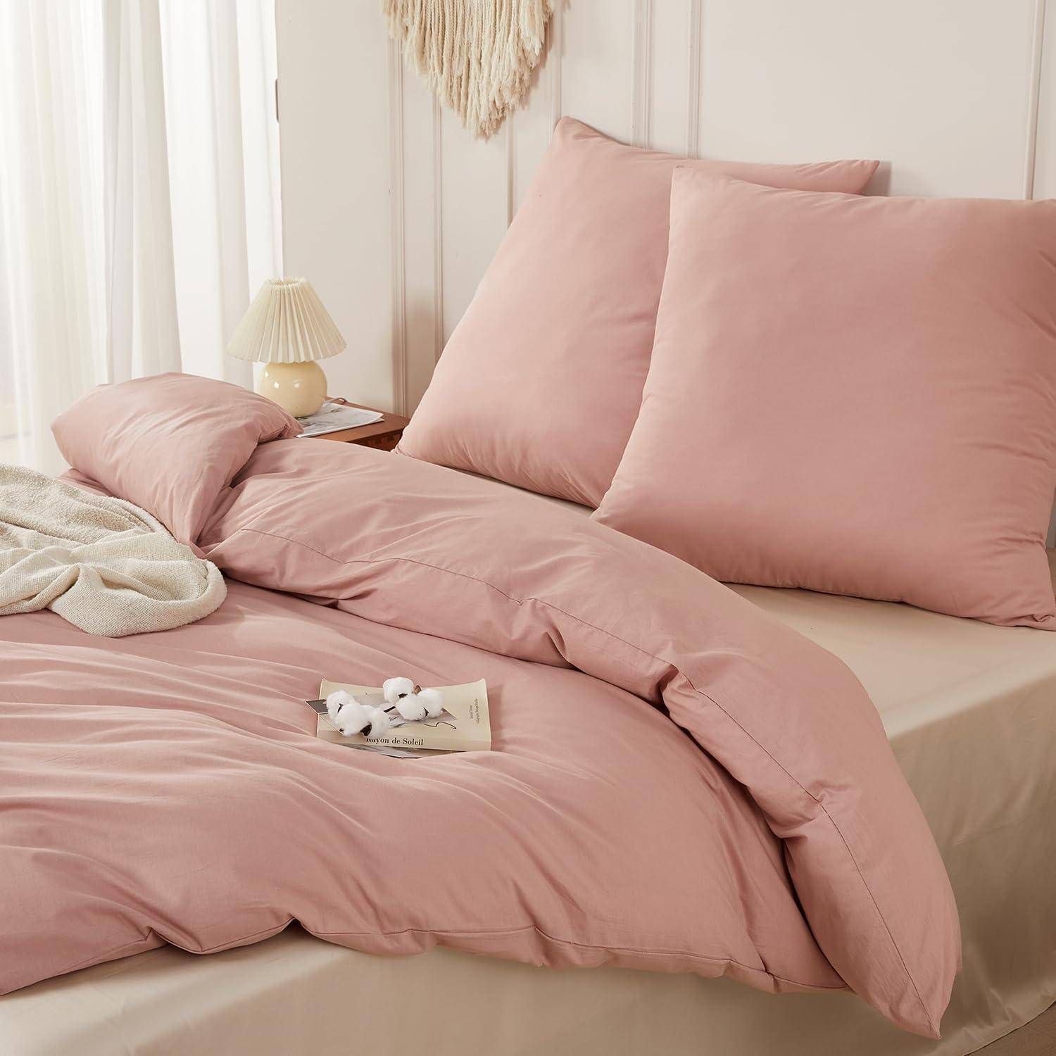 Rosafarbenes Bettwäscheset auf einem ordentlich gemachten Bett mit passenden Kissen, Bettdecke und Laken in einem weichen, minimalistischen Schlafzimmer.