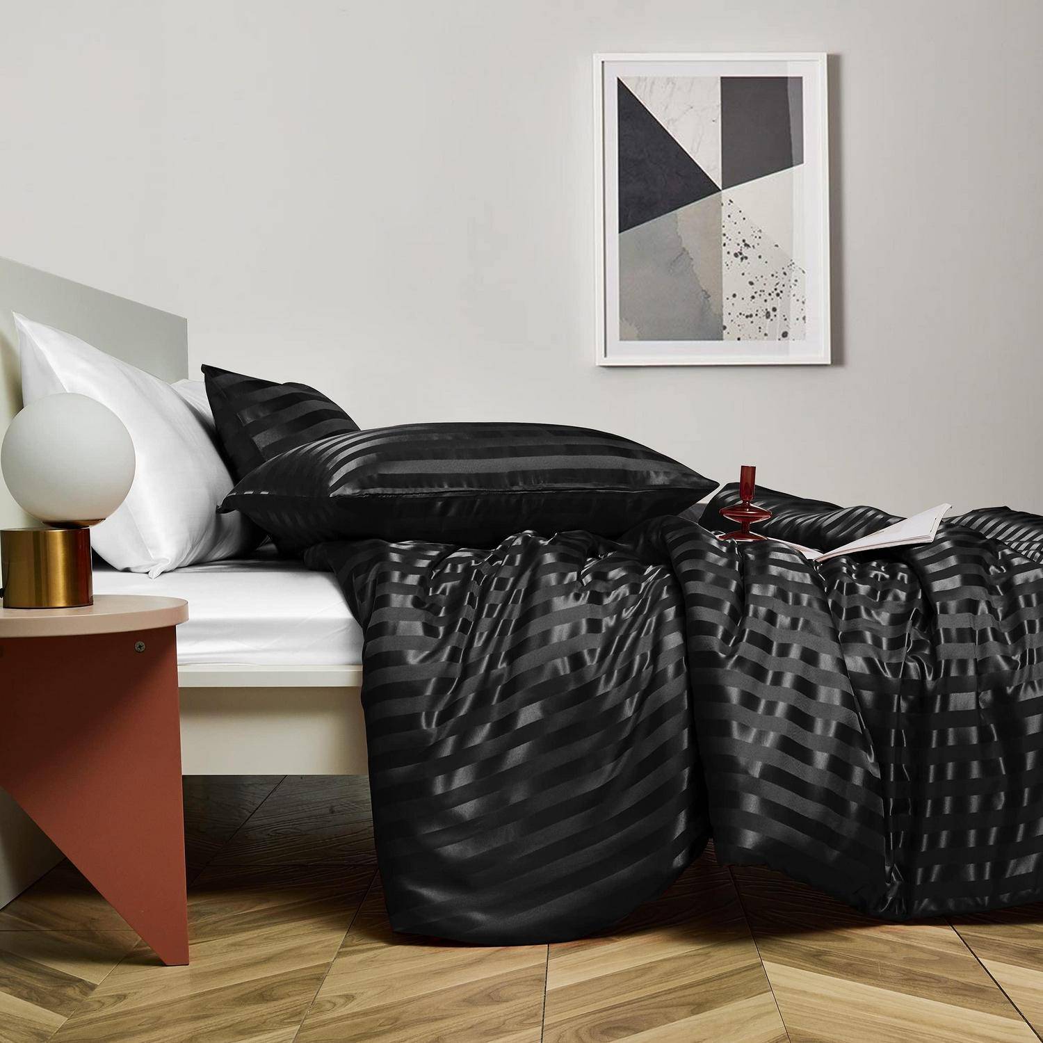 Modernes Bett mit schwarz gestreifter Bettwäsche, weißem Kissen, Nachttischlampe und gerahmtem Wandbild in einem minimalistischen Schlafzimmer.