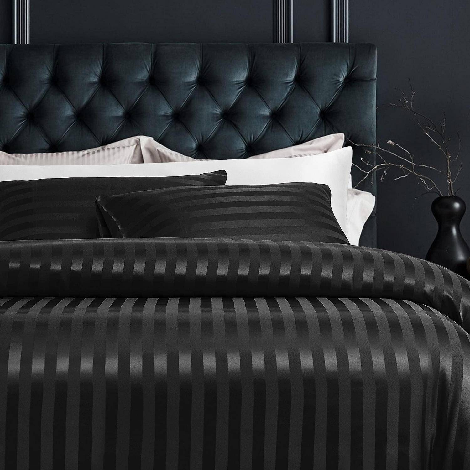 Schwarz gestreifte Bettwäsche auf einem Bett mit gepolstertem schwarzem Lederkopfteil, vor einer dunklen Schlafzimmerwand mit einer Vase auf der rechten Seite.