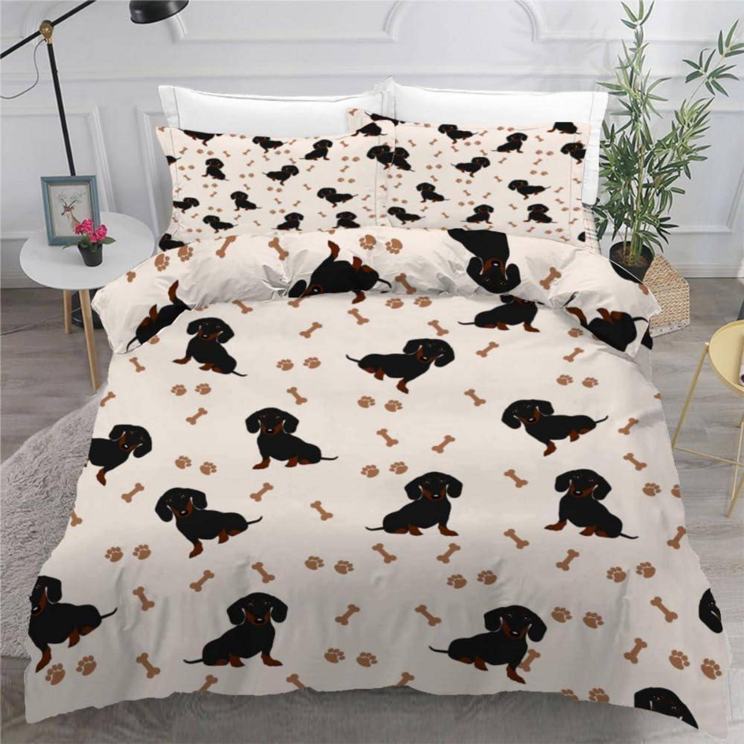 Bett mit Dackelmustern-Daunendecke und passenden Kissenbezügen in einem hellen Schlafzimmer, mit schwarzen und braunen Hunden und Pfotenbdrücken auf weißem Hintergrund