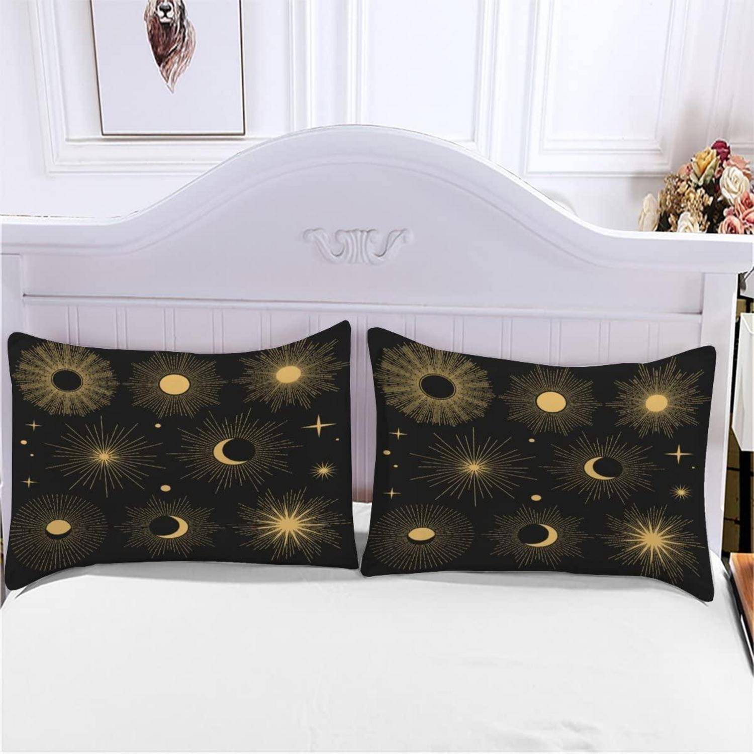 Bett mit zwei schwarzen Kissenbezügen mit gold Sonne-, Mond- und Strahlenmustern vor einem weißen Kopfteil
