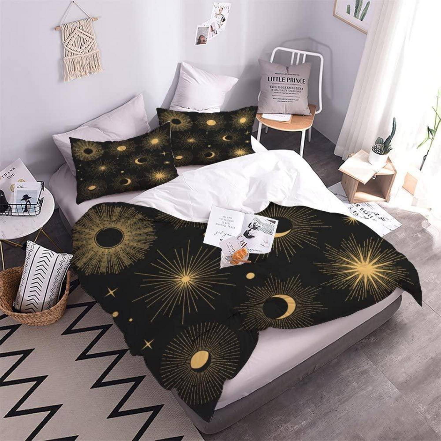 Modernes Schlafzimmer mit einem Bett, das in schwarzer und goldener Himmelsbettwäsche mit Sonne, Mond und Strahlenmuster gekleidet ist, mit Kissen und Seitendekoration.