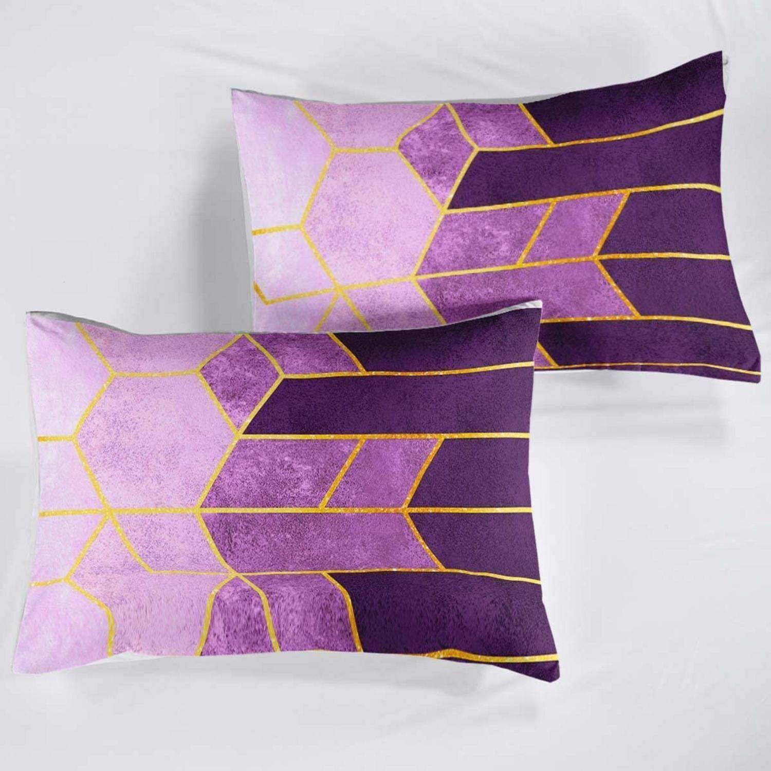 Zwei lila gemusterte Dekokissen mit goldenen geometrischen Linien auf hellgrauem Hintergrund.