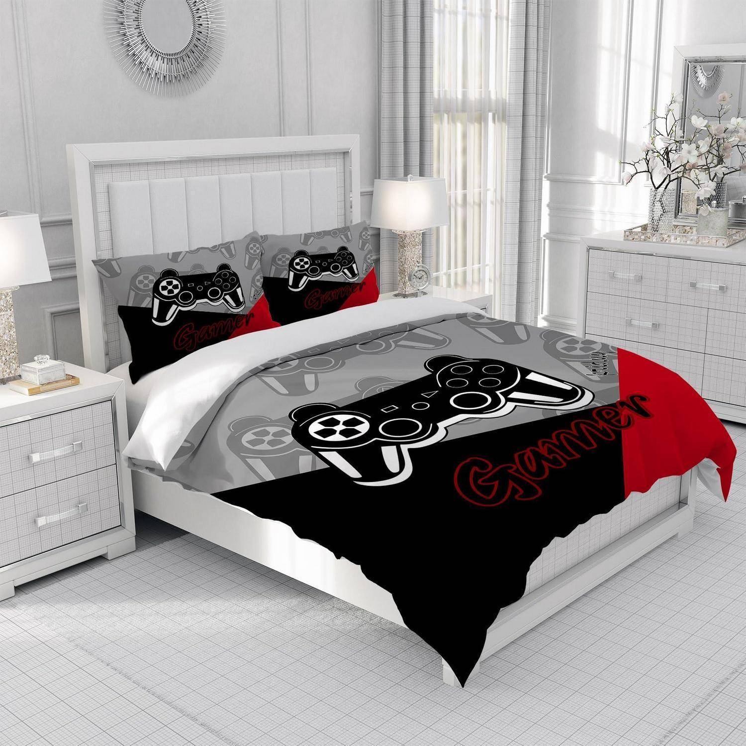 Bett mit Gaming-Themen-Bettdecke und passenden Kissen in einem hellen weißen Schlafzimmer, mit schwarzer Controller-Grafik und "Gamer""-Text.