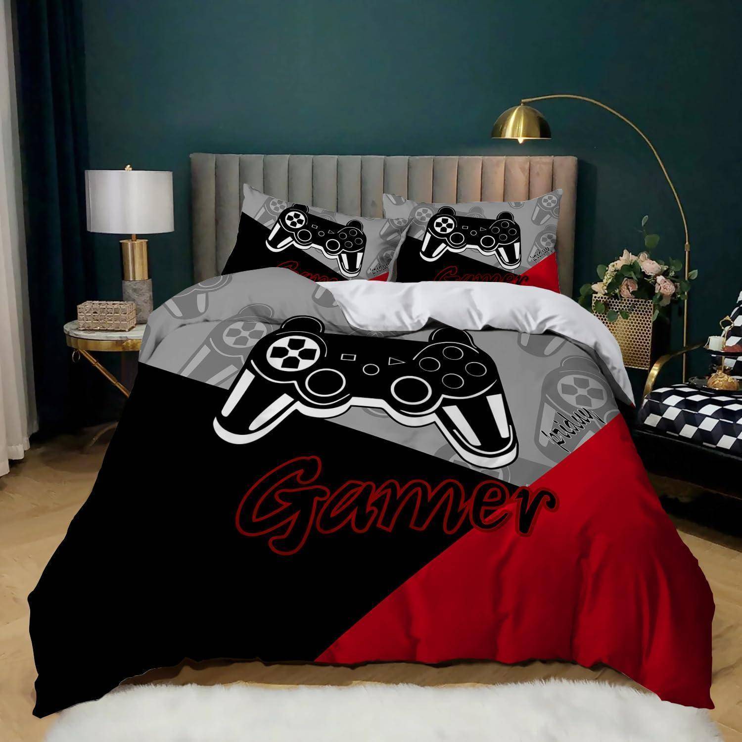 Ein Gaming-betont gestaltetes Bettwäsche-Set mit schwarzer, grauer und roter Bettwäsche, das Grafiken von Video-Spiel-Controllern und das Wort „Gamer" auf der Steppdecke zeigt.
