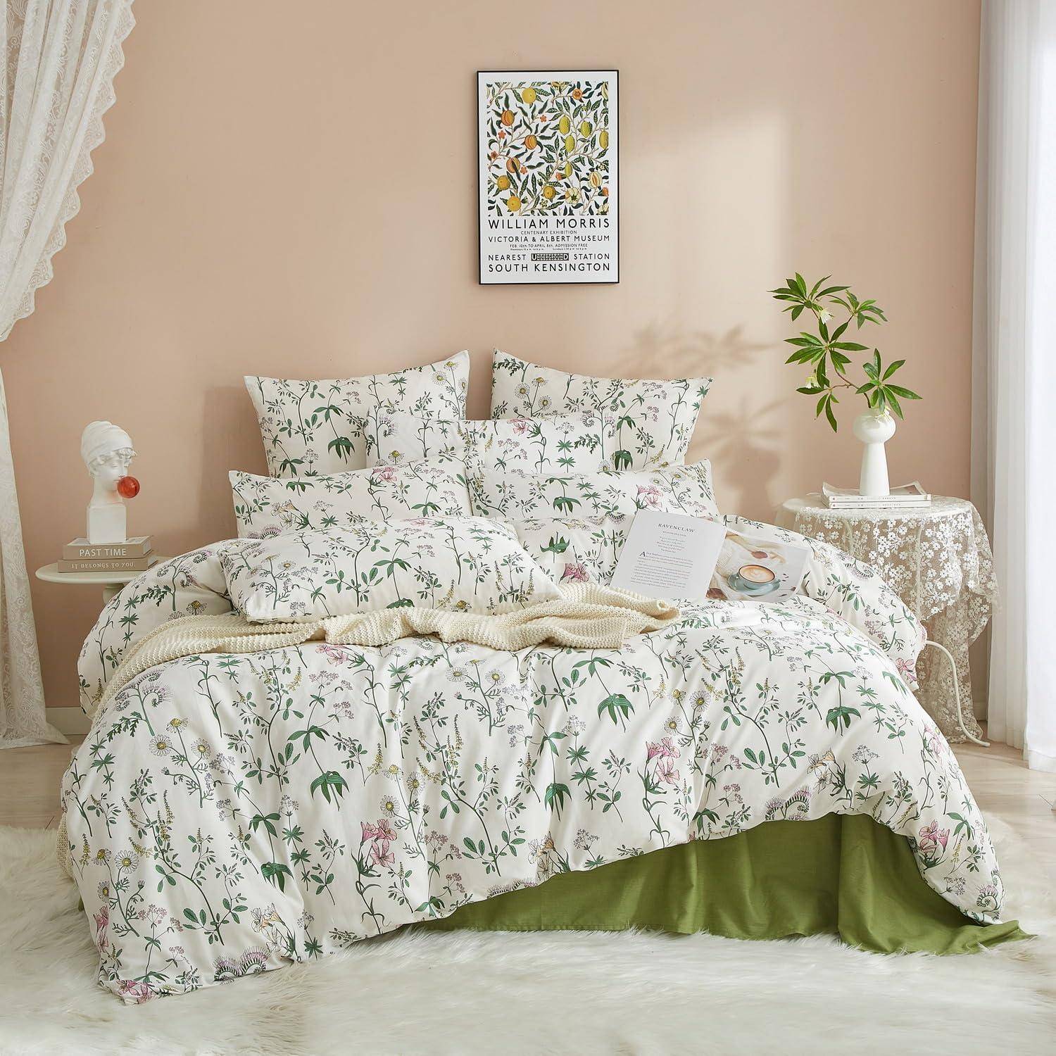 Ein sorgfältig gemachtes Bett mit weißer Blumenbettwäsche und grünen Akzenten in einem Pastellschlafzimmer, mit einem gerahmten William-Morris-Druck darüber und Nachttischen mit Dekoration.