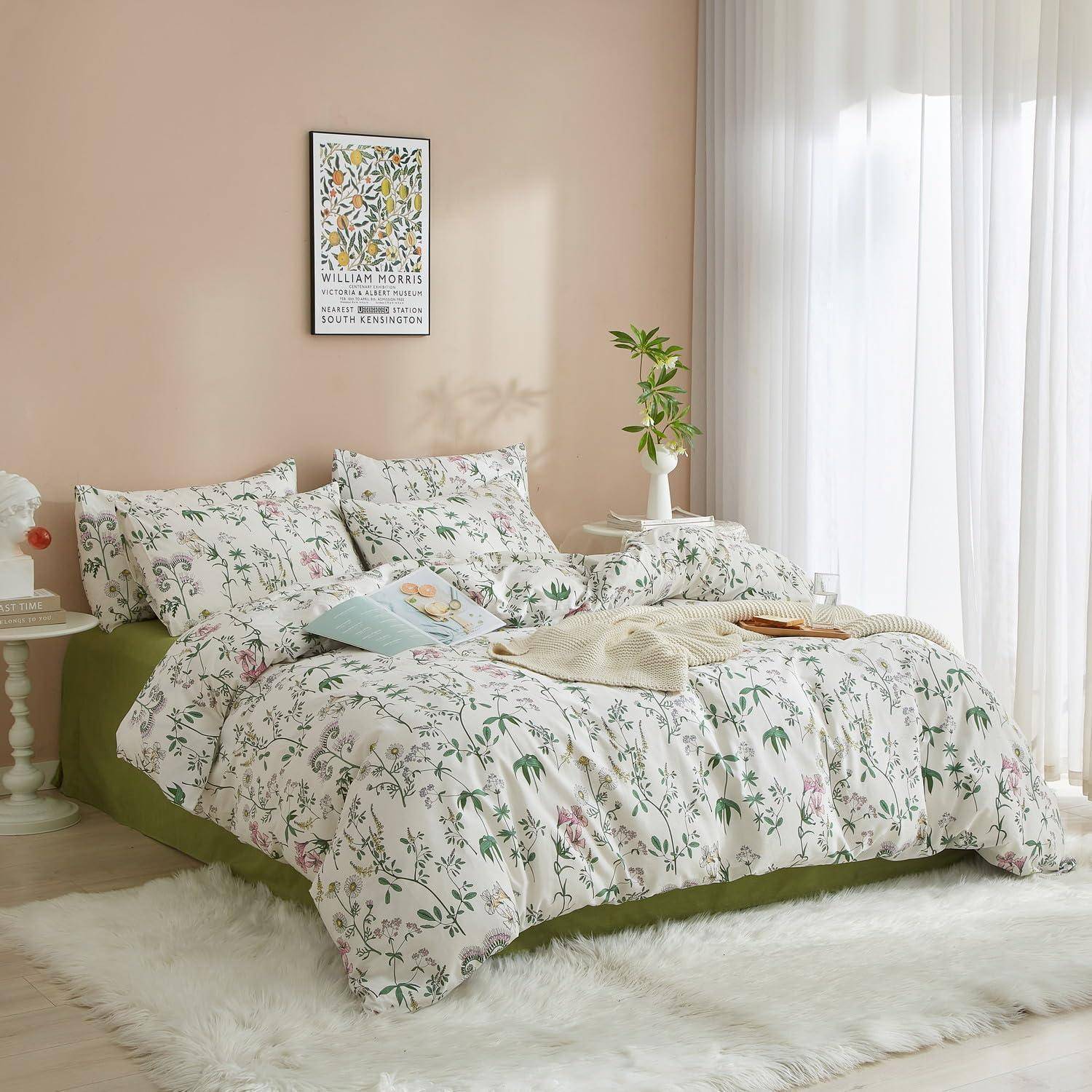 Blumenmuster-Bett mit passenden Kissen und Bettdecke in einem weichen, pastellfarbenen Schlafzimmer, neben einem Fenster mit transparenten Vorhängen und einer kleinen Pflanze.