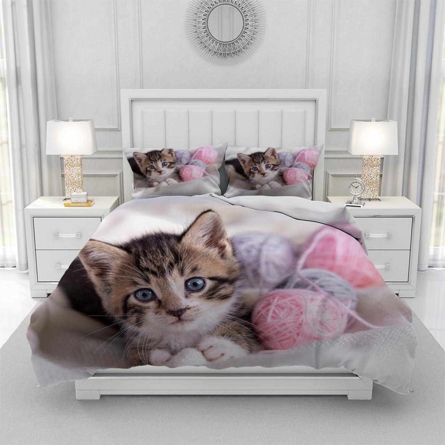 Ein Bett mit katzenthematischer Bettwäsche, mit einem großen Katzenbild auf der Bettdecke und passenden Kissen in einem weißen Schlafzimmer mit Nachttischlampen.