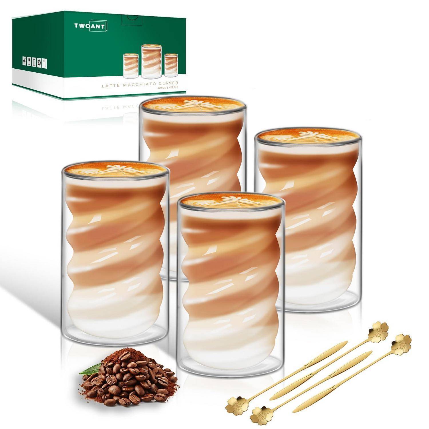 Vier Latte-Macchiato-Glastassen mit geschichtetetem Kaffee und Milch, gezeigt mit einer grünen Produktschachtel, Kaffeebohnen und Rührstäbchen.