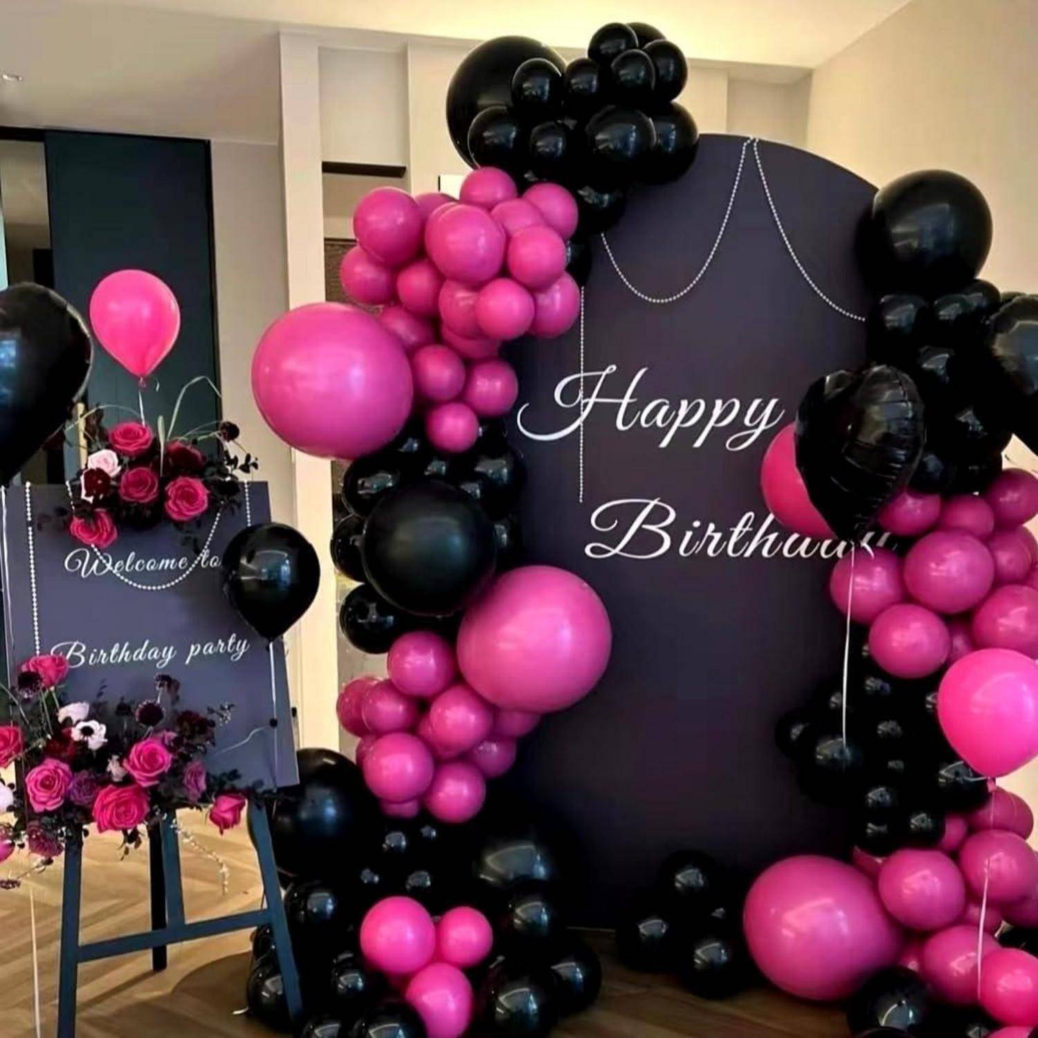 Geburtstagsfeier-Dekoration mit schwarzen und rosa Ballon-Bögen rund um einen 