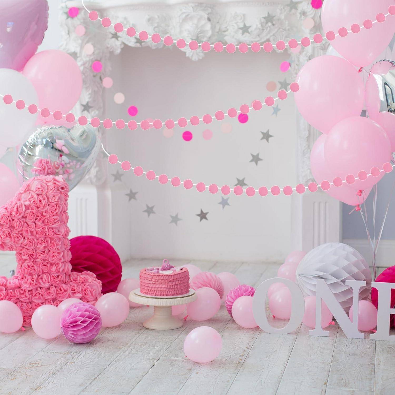 Rosa Erste-Geburtstags-Party-Setup mit Ballongirlanden, Stern-Hintergrund, Kuchen auf einem Ständer und großen "EINS""-Buchstaben