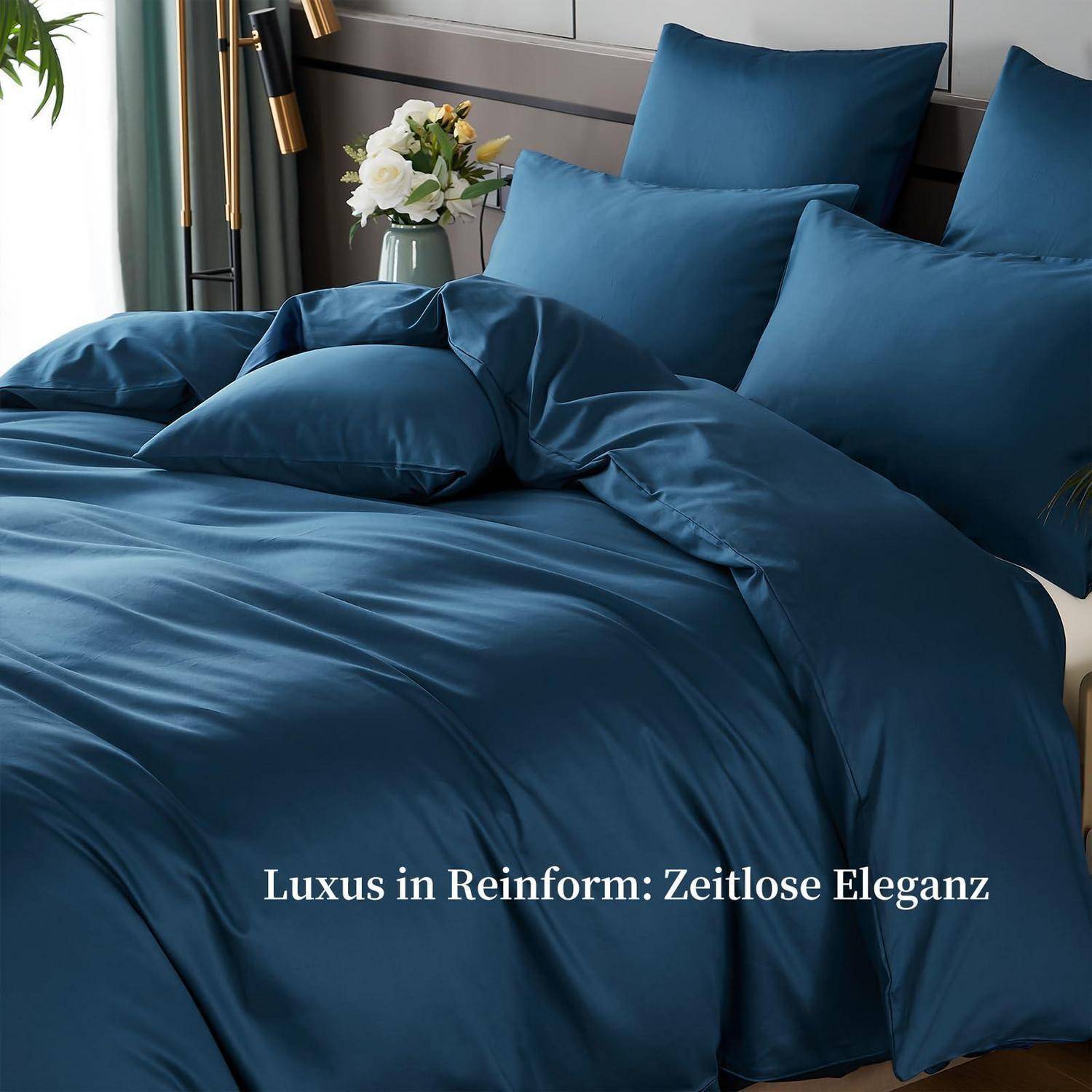 Blaue, seidenartig wirkende Bettwäsche auf einem gemachten Bett mit Kissen; übergelagerter Text lautet „Luxus in Reinform: Zeitlose Eleganz".