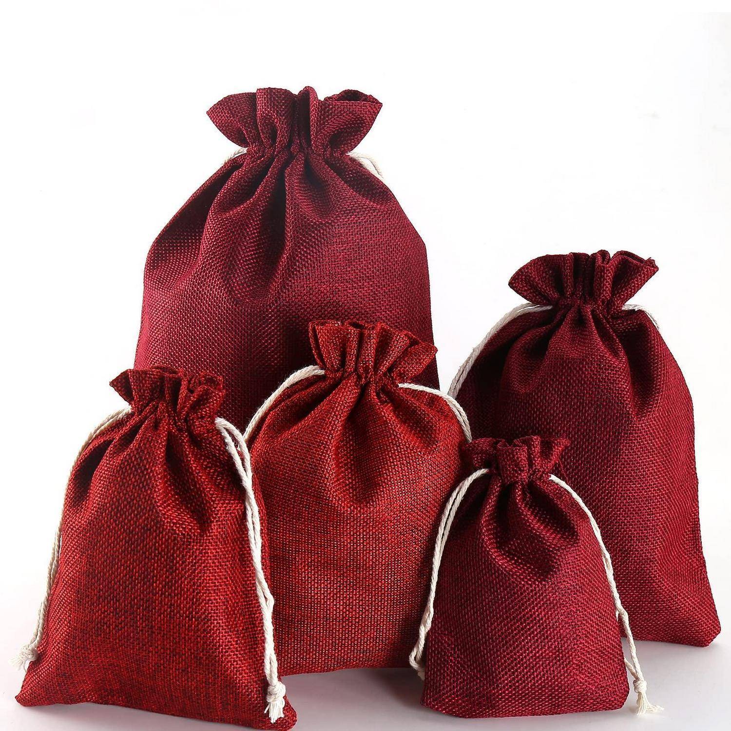 Fünf rote Stoffgeschenktaschen mit Kordelzug in verschiedenen Größen, angeordnet zusammen auf weißem Hintergrund.