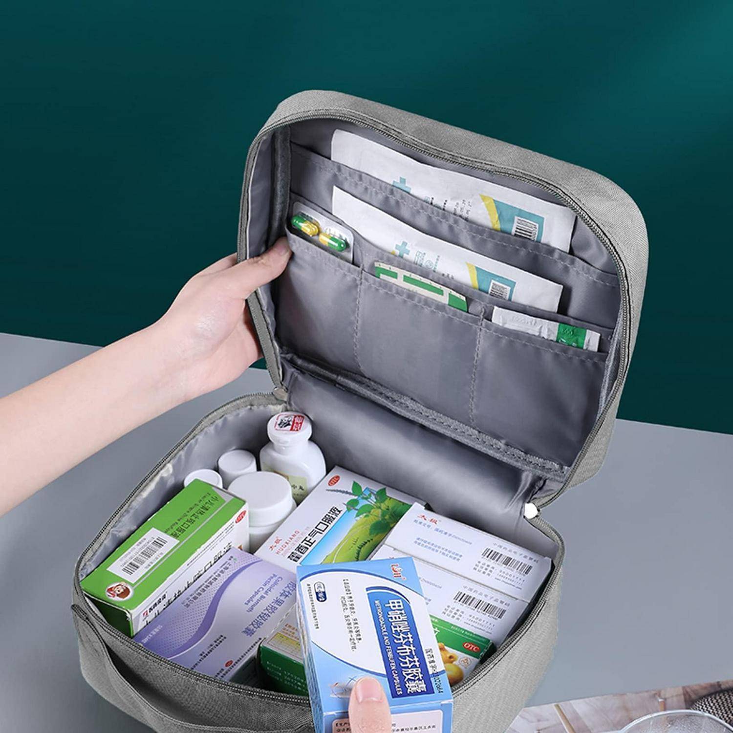 Offene graue Kosmetiktasche gefüllt mit Medikamentenboxen, Flaschen und Päckchen, die eine organisierte Aufbewahrung für Reisen oder Erste Hilfe zeigt.
