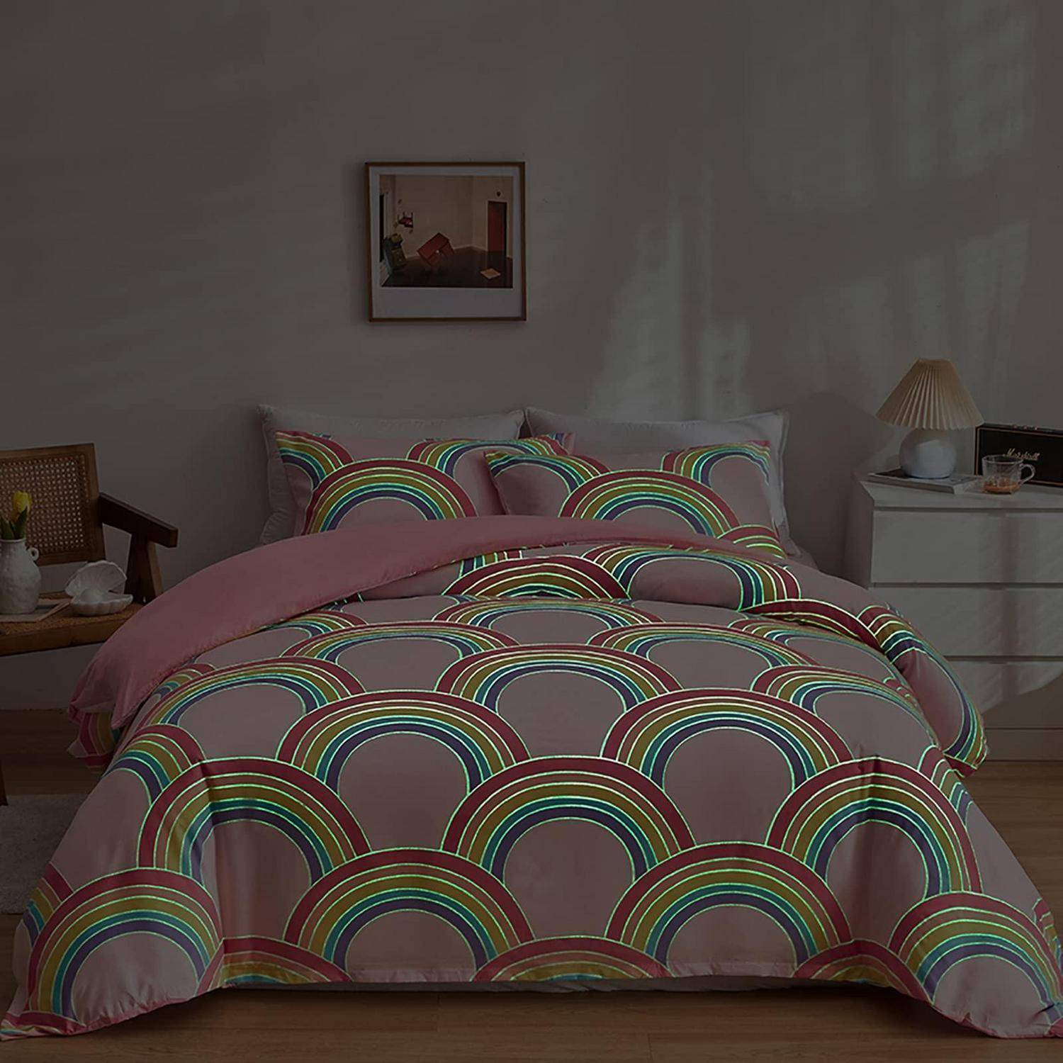 Ein ordentlich gemachtes Bett mit regenbogenfarbenem Bettzeug und rosa Decke in einem sanft beleuchteten Schlafzimmer mit Nachttischen und Wandkunst.