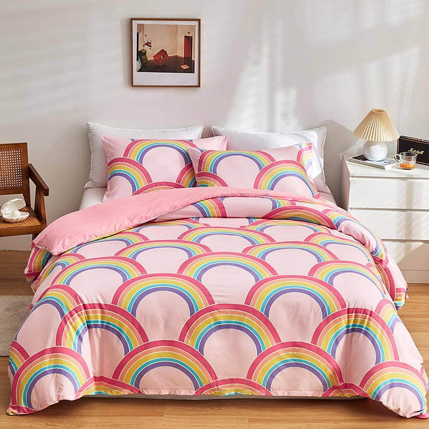 Bett mit rosa Regenbogenmuster-Bettwäsche und passenden Kissen in einem hellen Schlafzimmer.