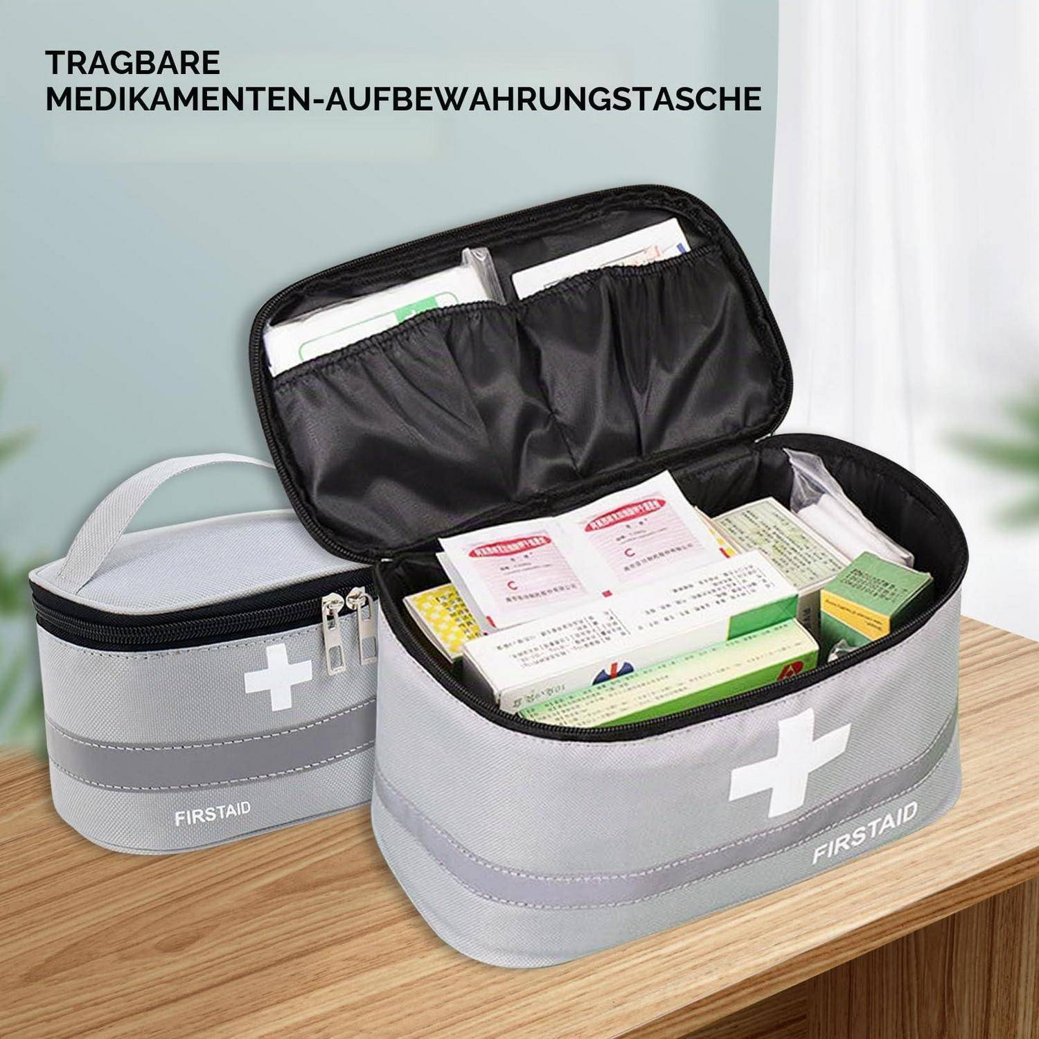 Offene graue Erste-Hilfe-Medikamentenlagerungstaschen auf einem Tisch, eine gefüllt mit Medikamentenboxen und Paketen, beschriftet mit „FIRSTAID".