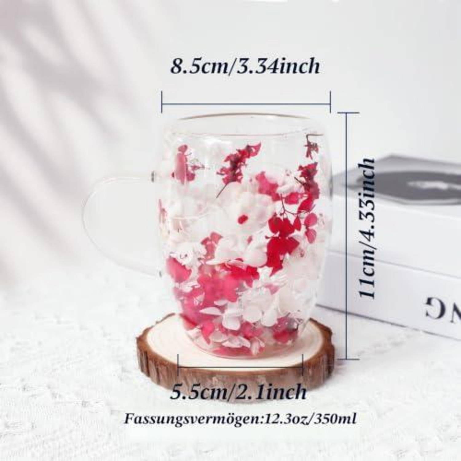 Transparente Glastasse mit herzförmigem Griff, gefüllt mit rosa und weißen Blütenblättern, mit Abmessungen von 8,5 cm Breite und 11 cm Höhe; Fassungsvermögen 350 ml.