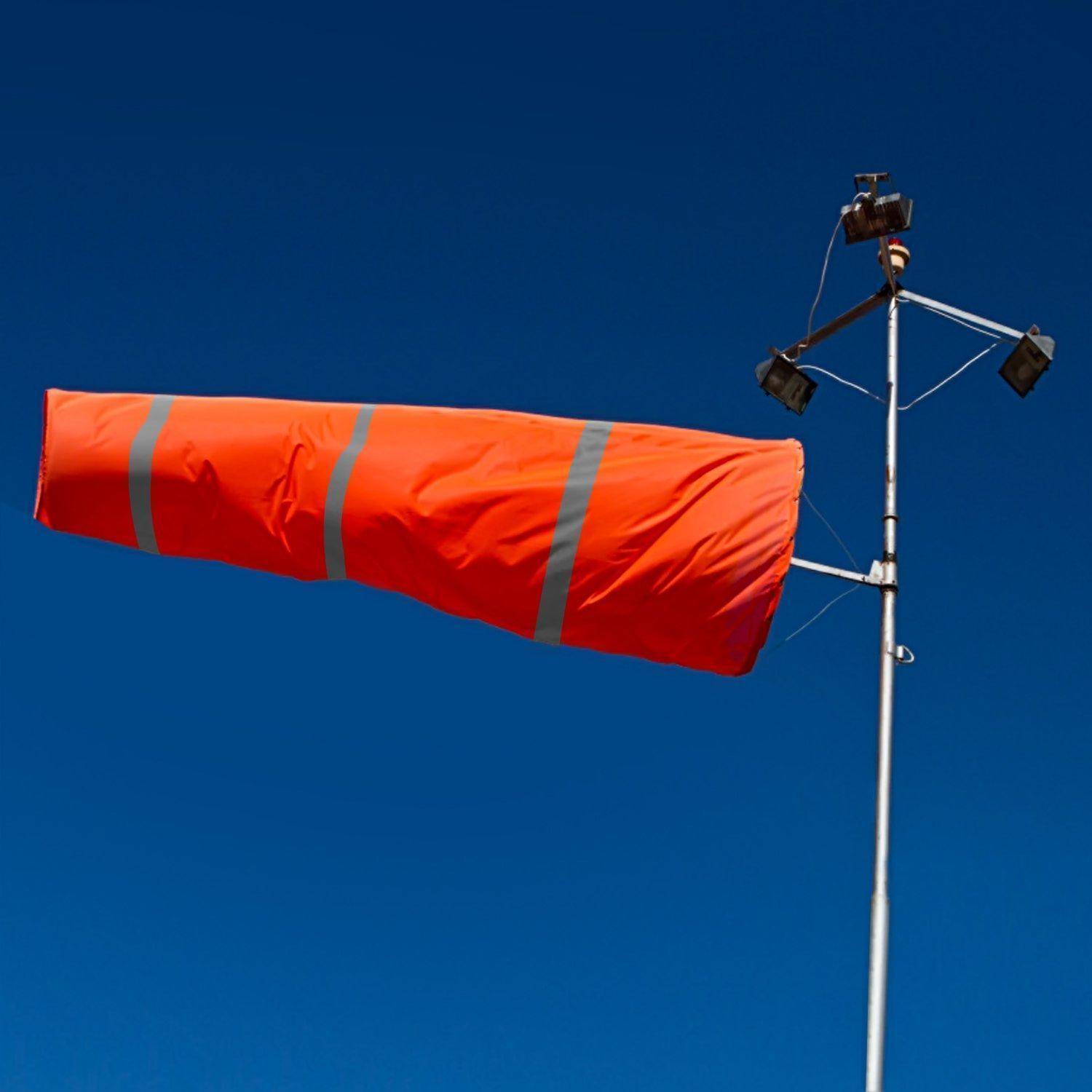 Orangefarbener Windsack auf einer Stange mit Sensorausrüstung, der die Windrichtung gegen einen klaren blauen Himmel anzeigt.