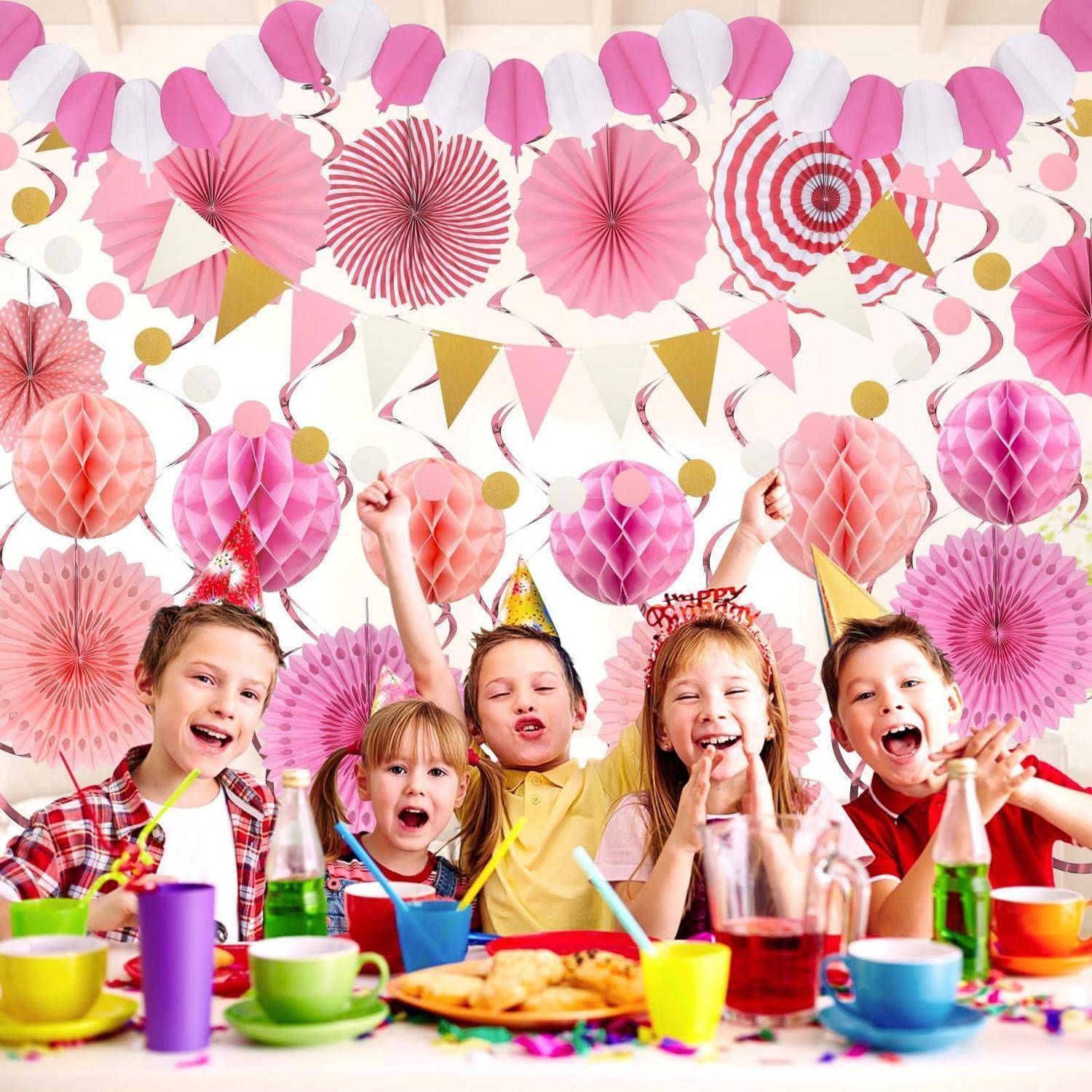 Vier Kinder an einem bunten Geburtstagspartytisch, lächelnd und Partyhüte tragend, mit festlichen rosa Dekorationen und Snacks im Hintergrund.