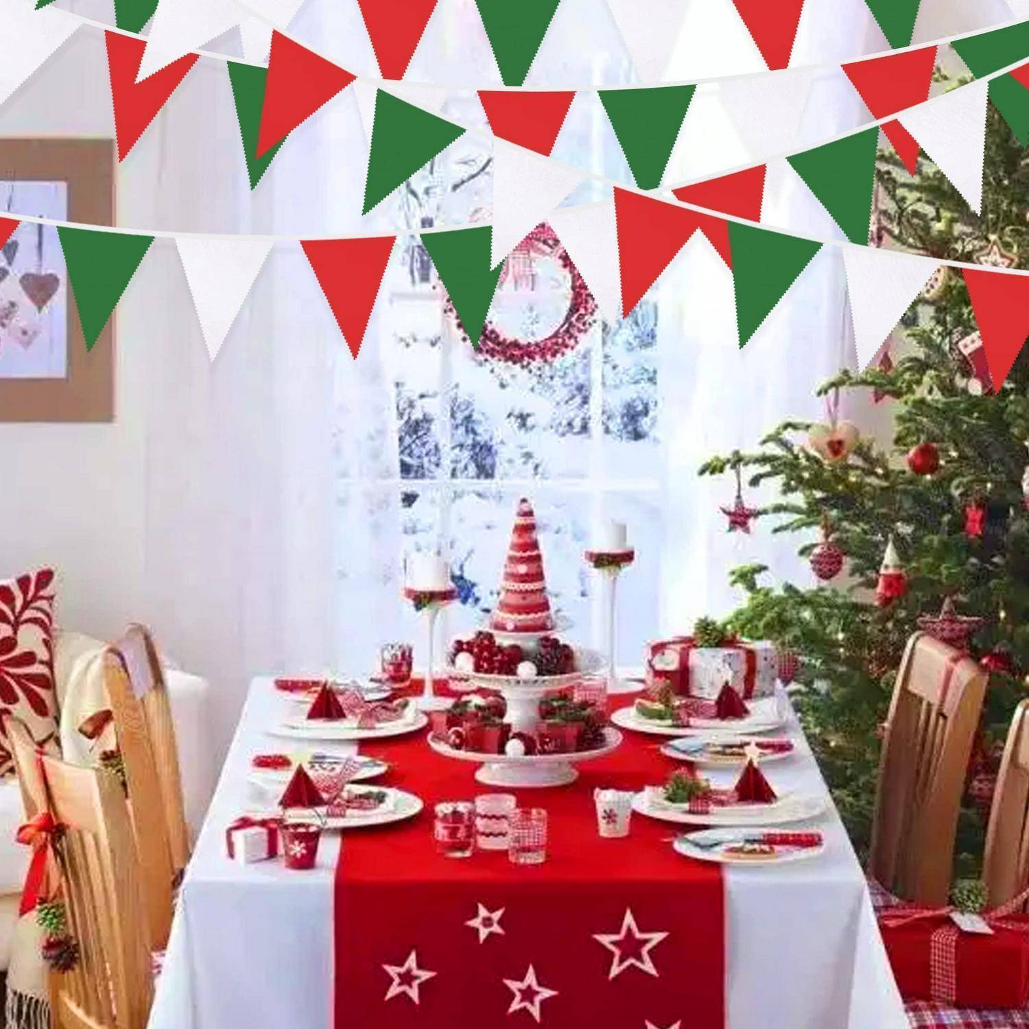 Festlich gedeckter Weihnachtsesstisch mit rot-weißen Dekorationen, Baum, Geschenken und Girlanden in einem hellen Raum.