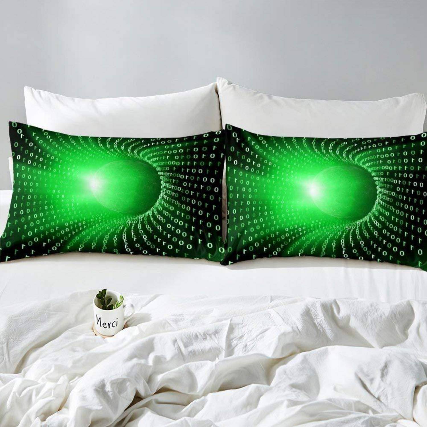 Weißes Bett mit zwei schwarz-grünen Mustern im Binärcode-Design und einer kleinen Topfpflanze mit der Aufschrift „Merci