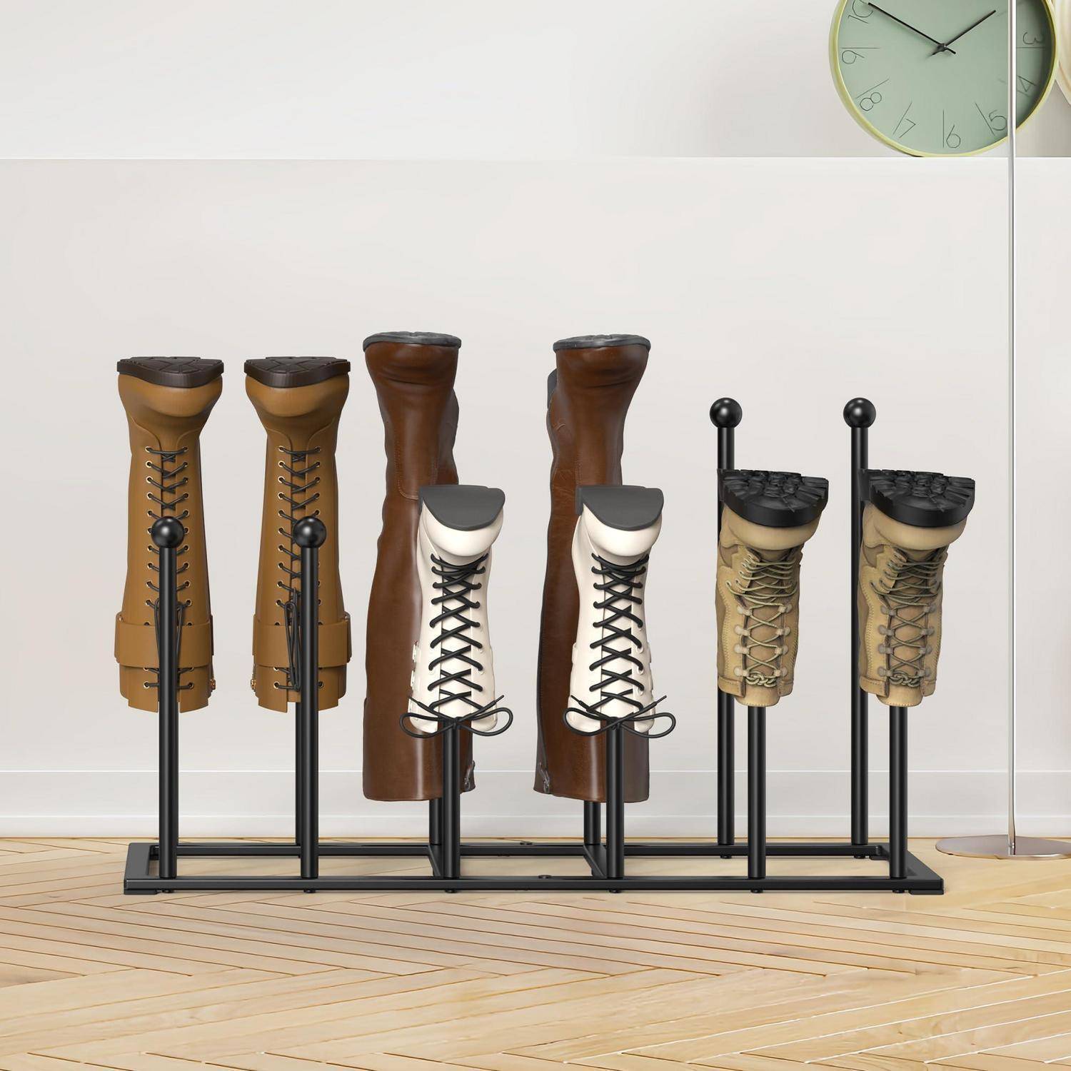 Reihe von sechs Lederstiefelständern mit Paaren brauner und beiger Stiefel auf einem schwarzen Metallregal, mit einer Wanduhr in der Ecke.