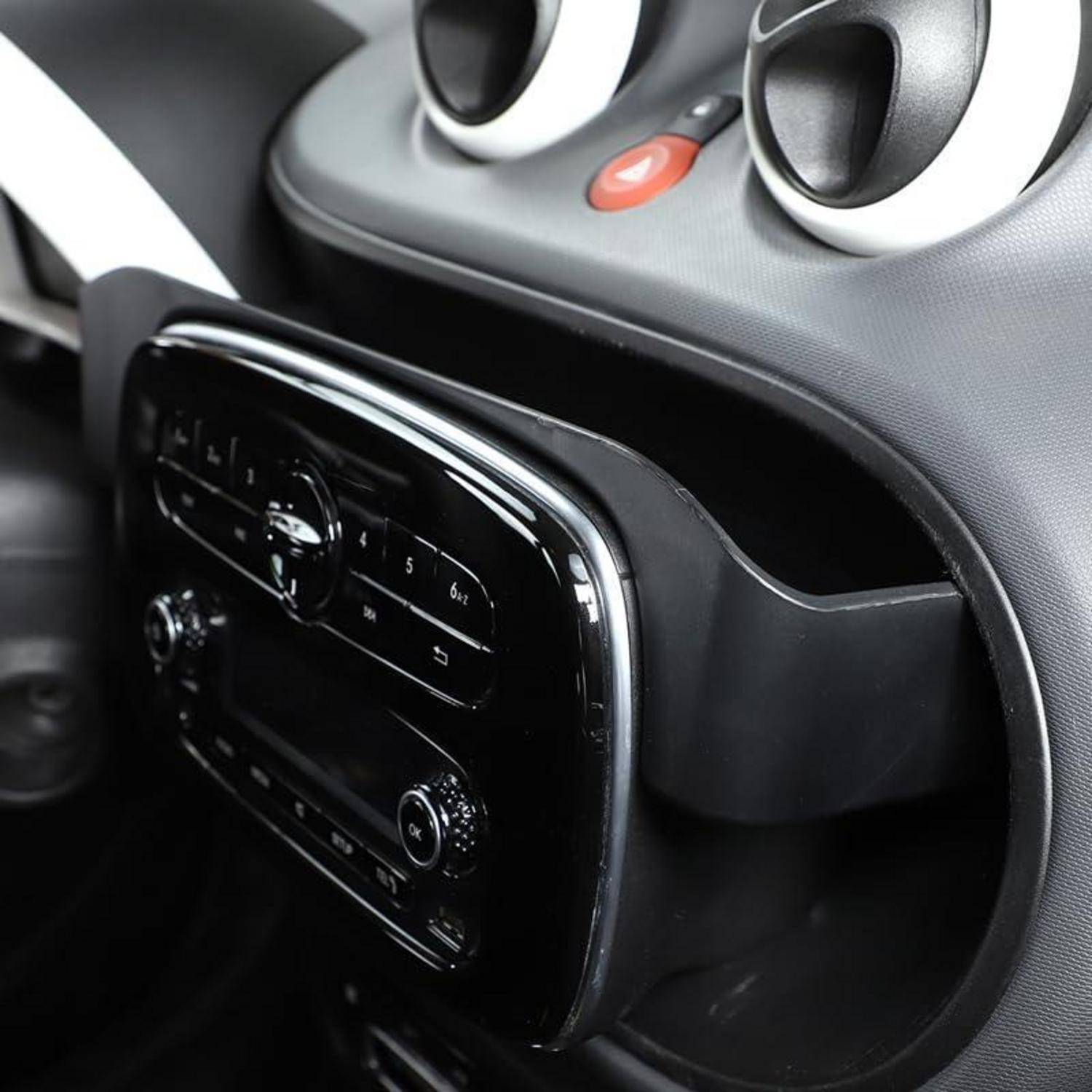 Nahaufnahme der mittleren Instrumententafel eines Autos mit schwarzem Infotainment- und Klimasteuerfeld unter kreisförmigen Lüftungsöffnungen und Warnblinkerschalter.
