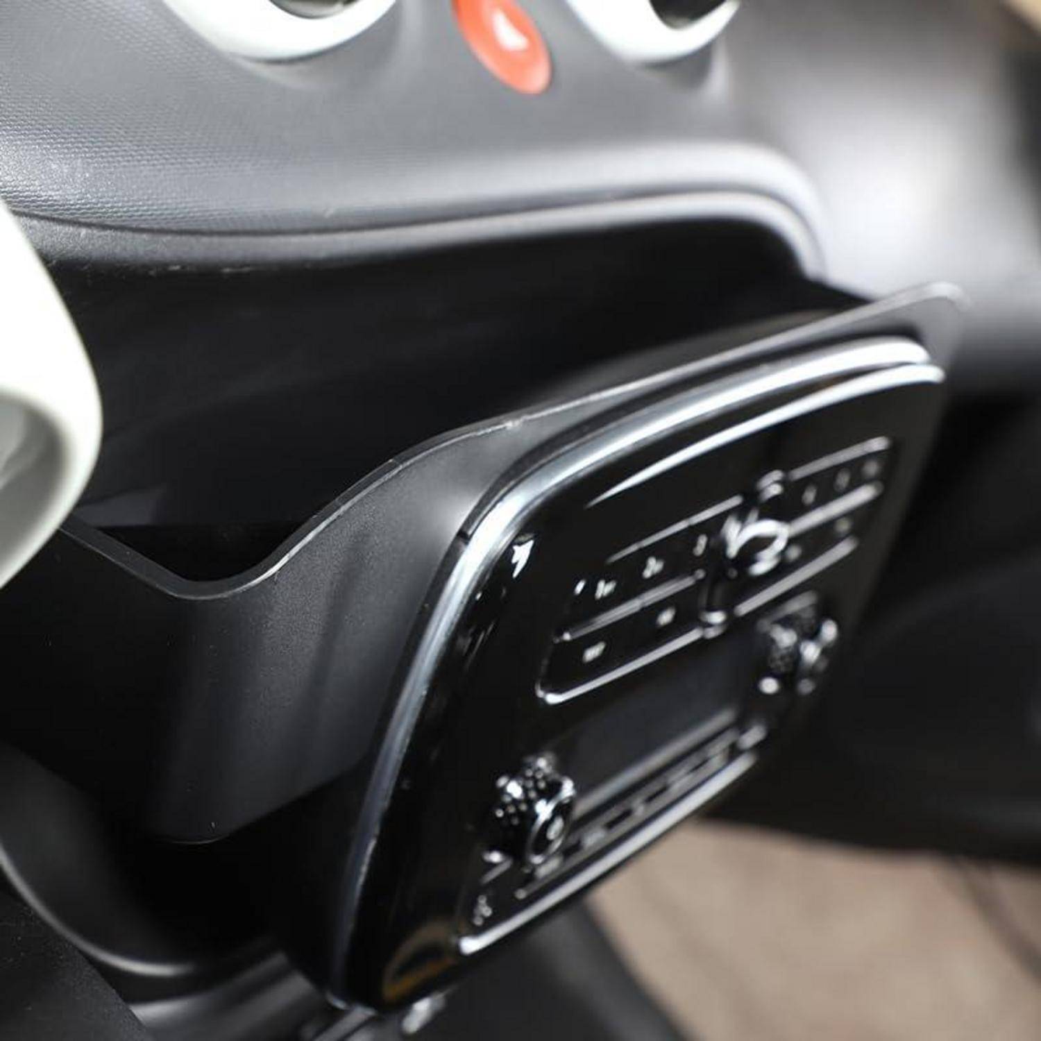 Nahaufnahme einer Mittelkonsole eines Autodashboards mit einem integrierten Klima- und Audiosteuerelement unter den Lüftungsöffnungen.