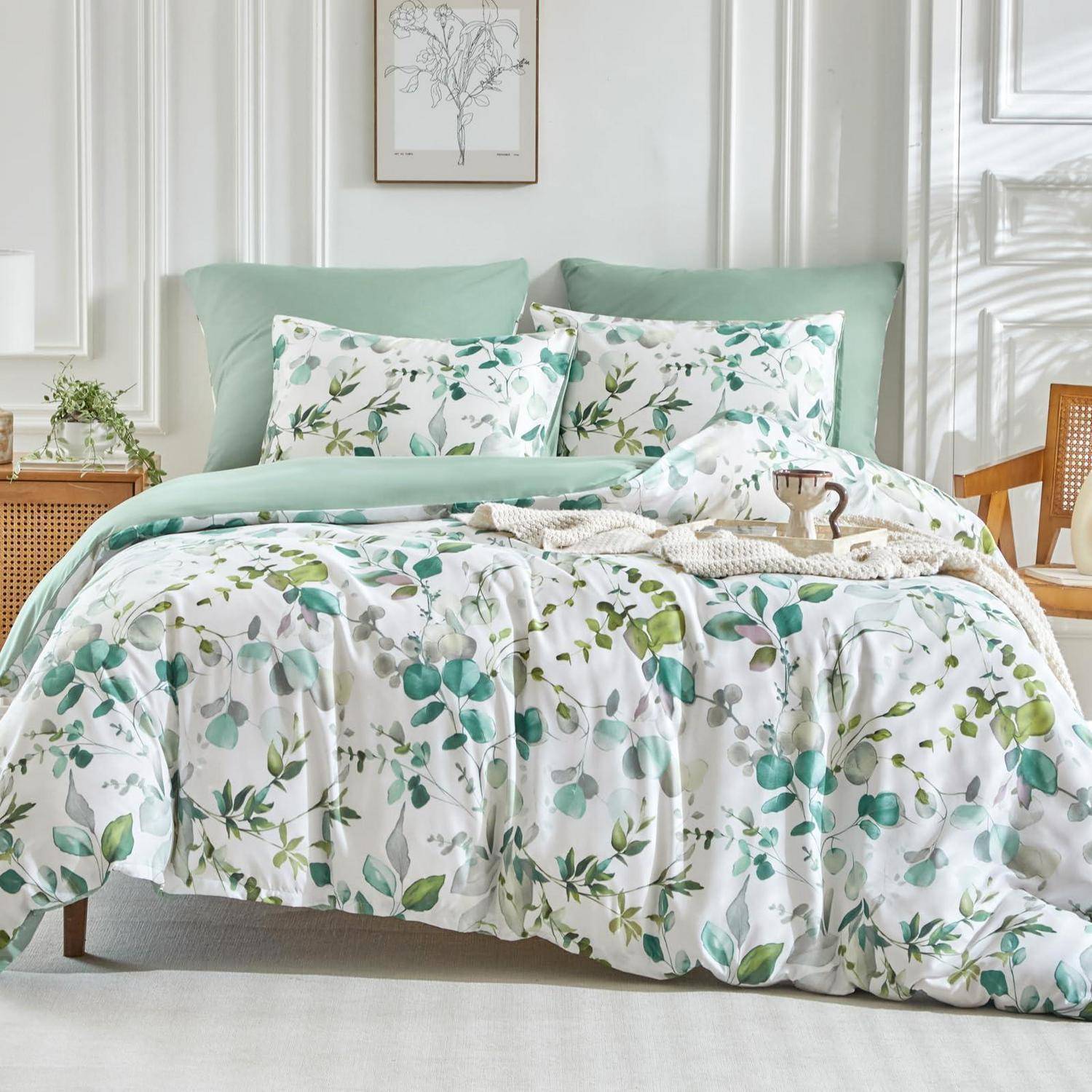 Bett mit mintgrüner Bettwäsche und Blattmuster sowie passenden Kissen in einem hellen, minimalistischen Schlafzimmer.