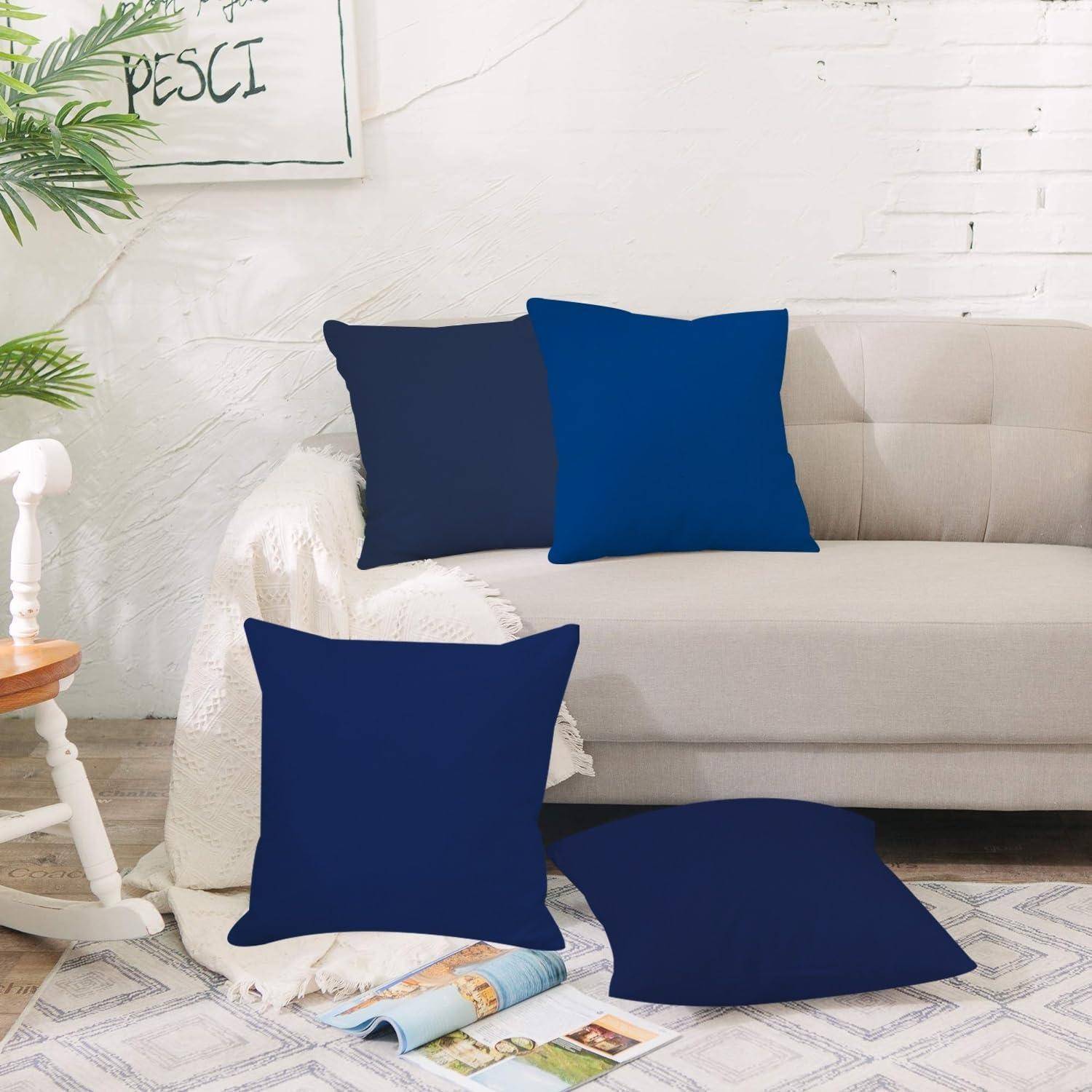 Wohnzimmersofas mit vier massiven dunkelblauem und blauem Wurfkissen gestylt, mit zwei Kissen auf der Couch und zwei auf dem Boden.