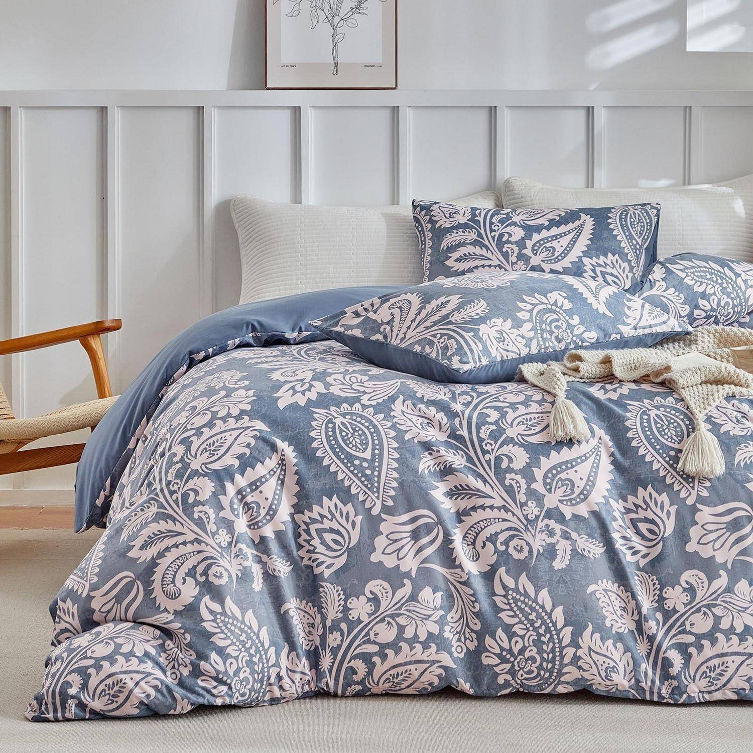 Ein ordentlich gemachtes Bett mit blau-weiß gemusterter Paisley-Bettwäsche und Kissen in einem hellen, minimalistischen Schlafzimmer.