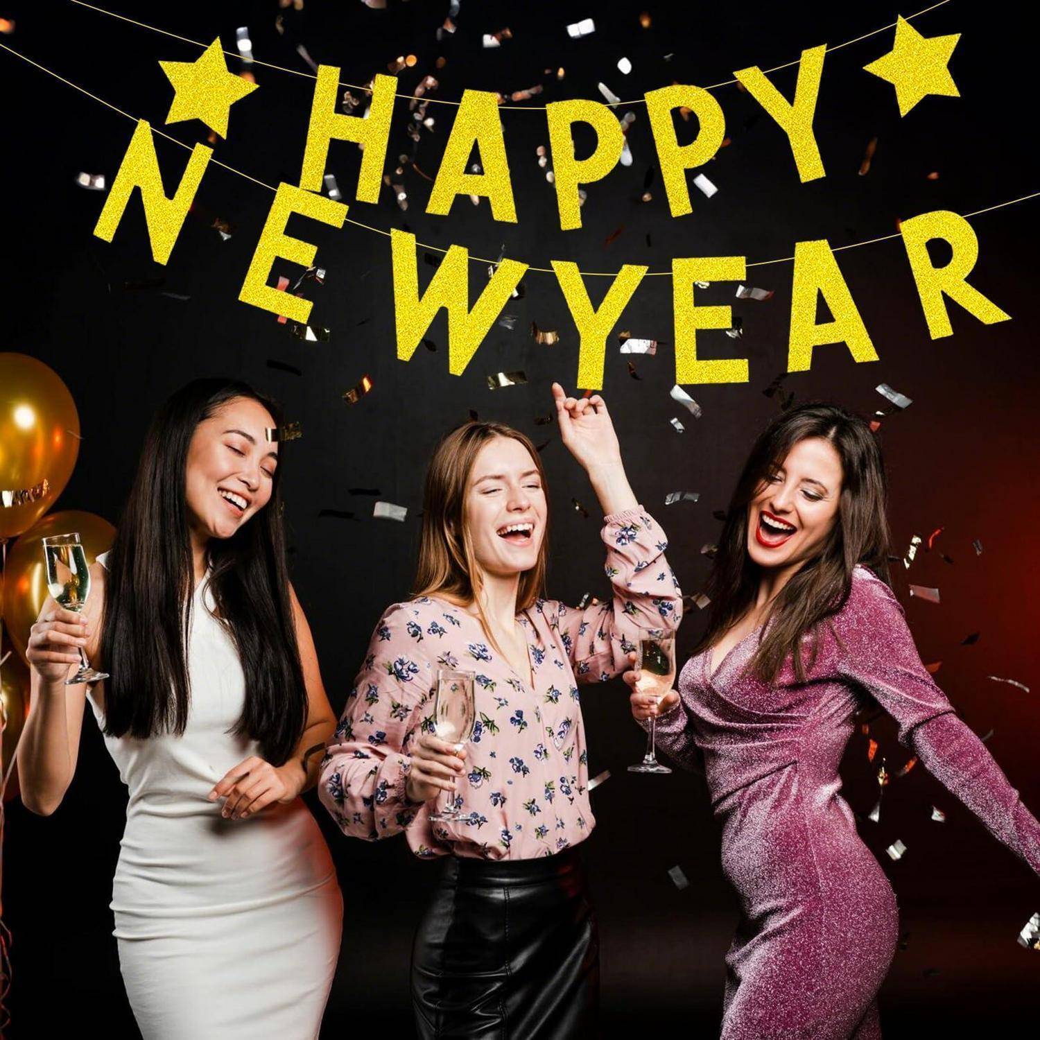 Drei Frauen feiern Silvester mit Champagner und Konfetti unter einem „HAPPY NEW YEAR
