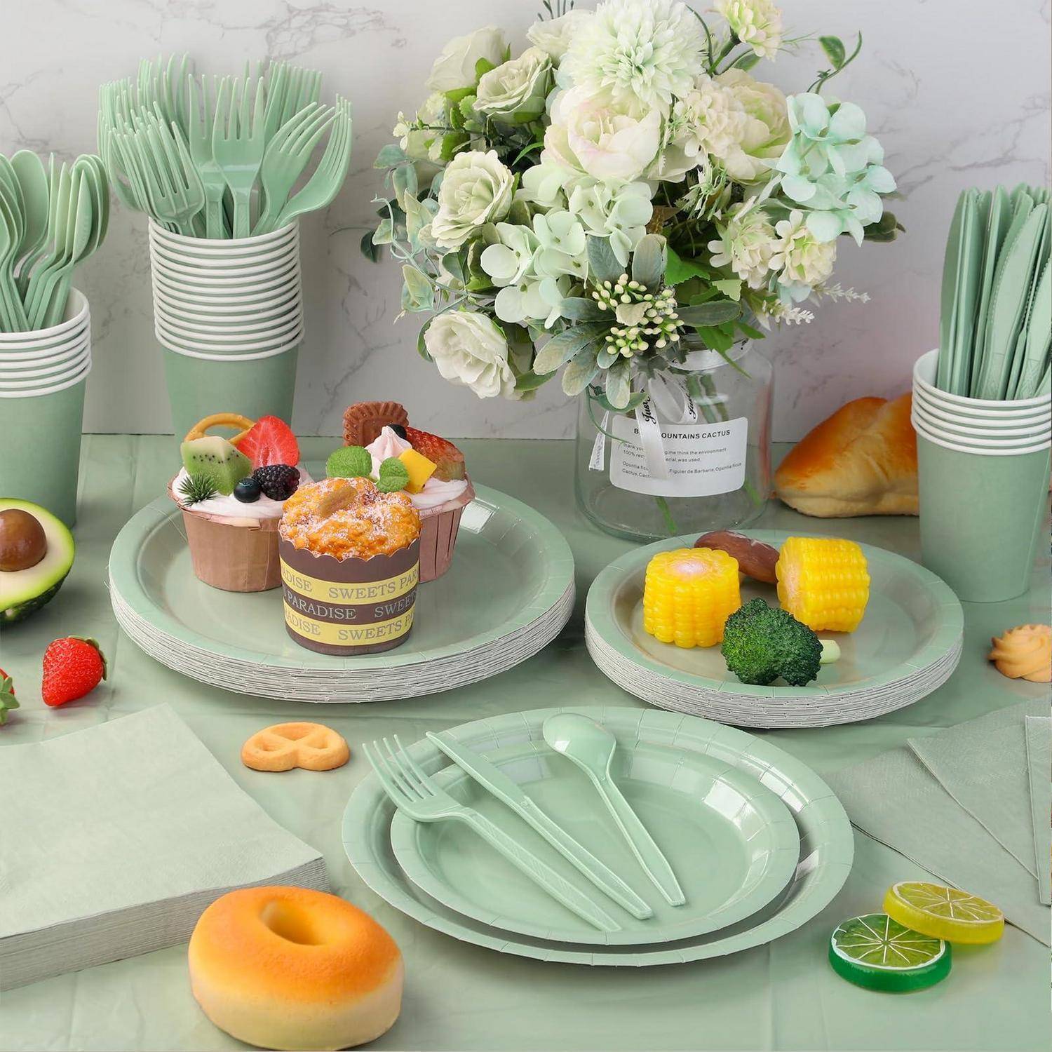 Tischanordnung mit Pastell-Desserts mit Cupcakes, fruchtbedeckten Kuchen, Mais am Spieß, gestapelten Tellern und Tassen sowie einem Blumen-Mittelstück.