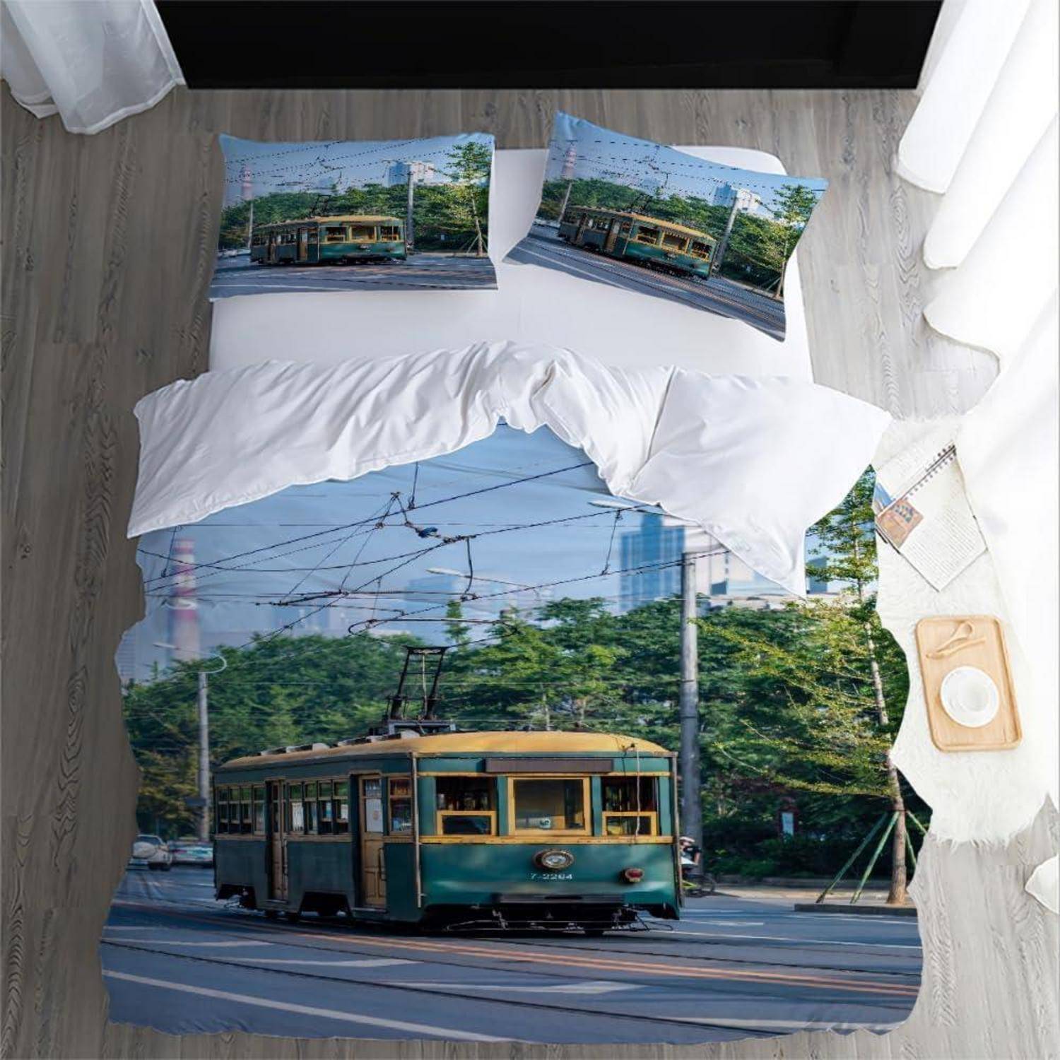 Ein Bett mit Straßenbahn-Thema-Bettwäsche und Kissen, das eine vintage grüne Straßenbahn auf Stadtgleisen zeigt.