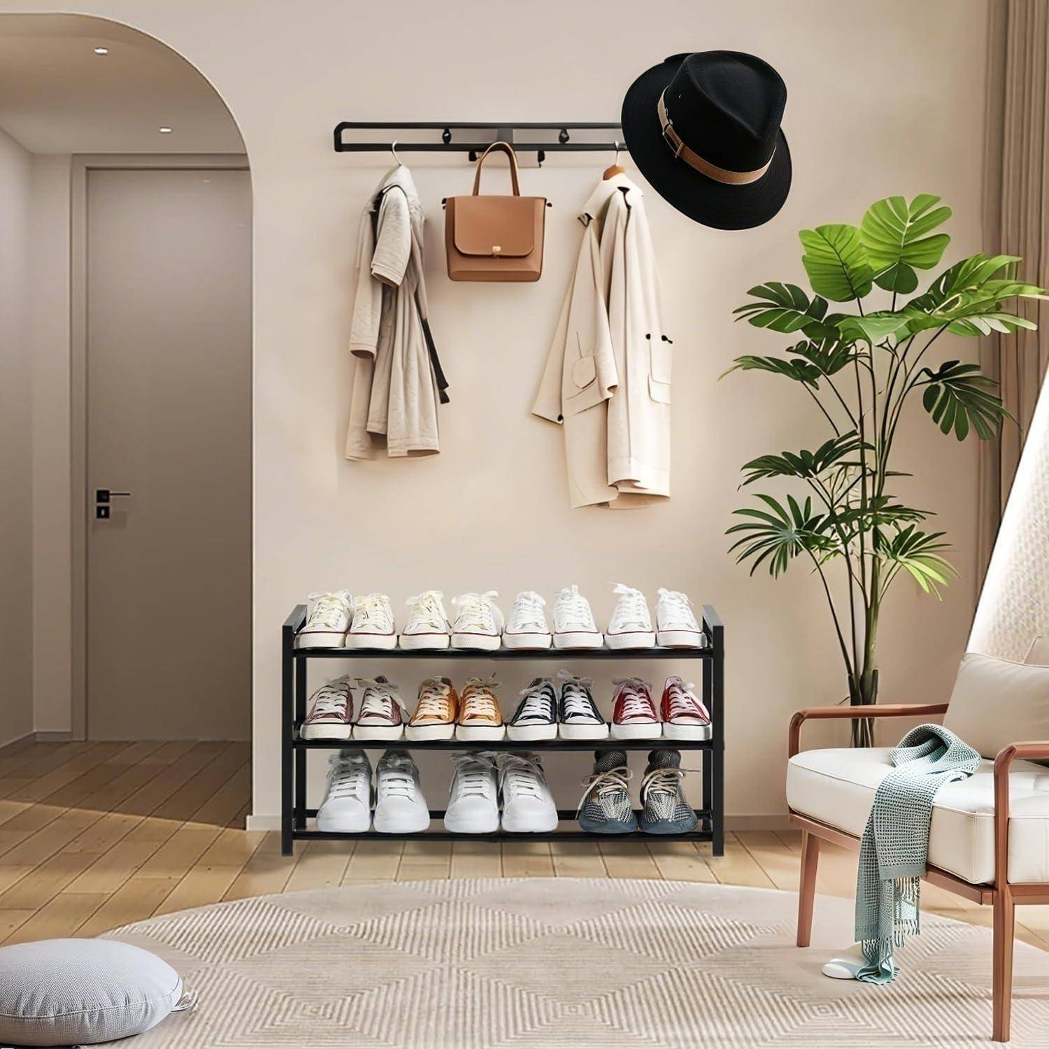 Stilvolle Eingangshalle mit Wandhaken, die Mäntel, eine Tasche und einen Hut halten, über einem Schuhregal, einer Topfpflanze und einer Bank mit drapierter Decke.