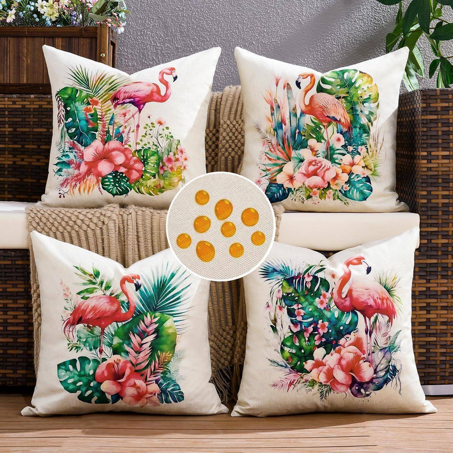 Vier dekorative weiße Flamingo- und tropische Blumen-Wurfelkissen, die um ein rundes Mittenkissen mit gelben Pünktchen auf einem Korbstuhl angeordnet sind.