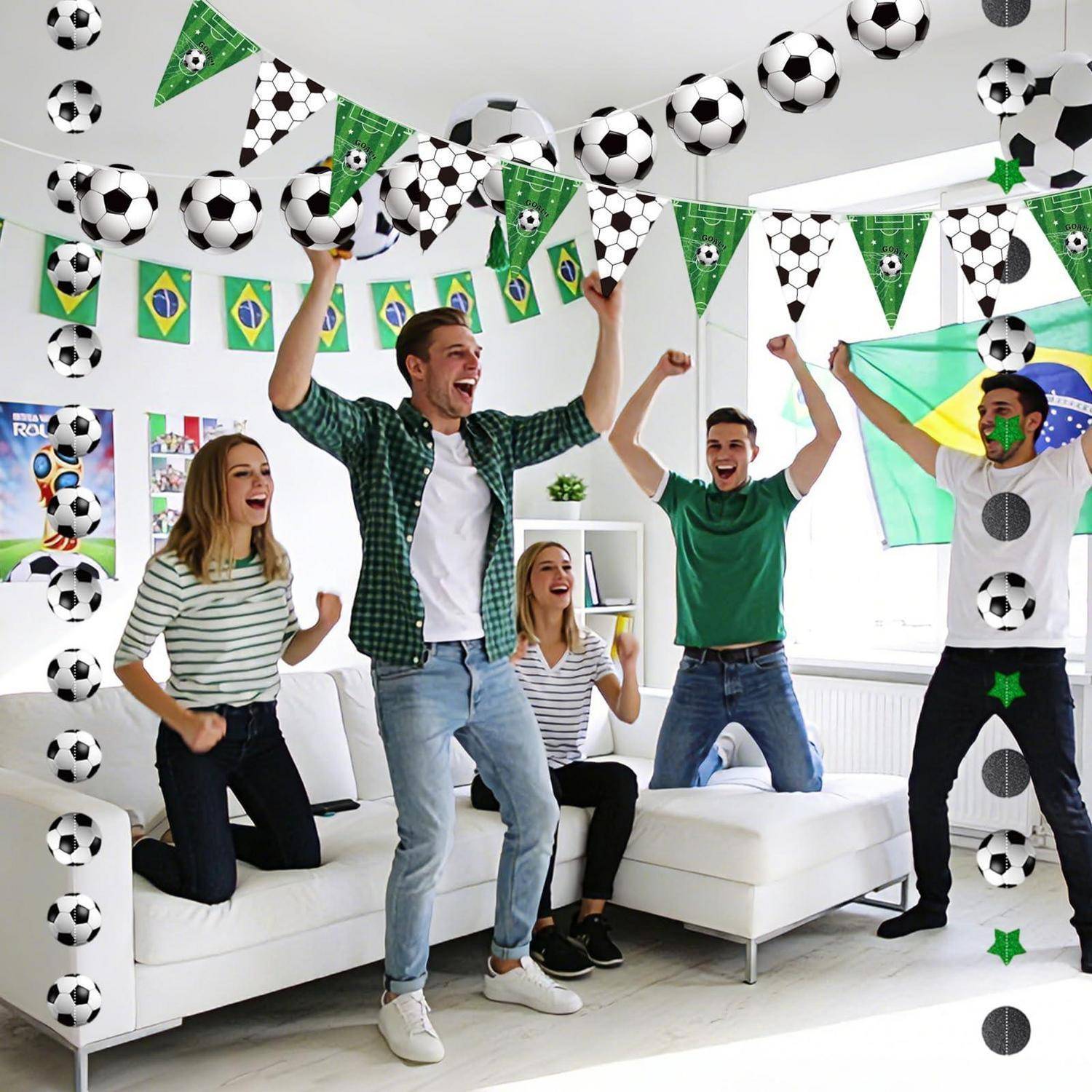 Gruppe von Freunden, die auf einer fußballthematischen Party in einem hellen Wohnzimmer jubeln, mit Fußballdekorationen und Brasilien-Flaggen, die overhead hängen.