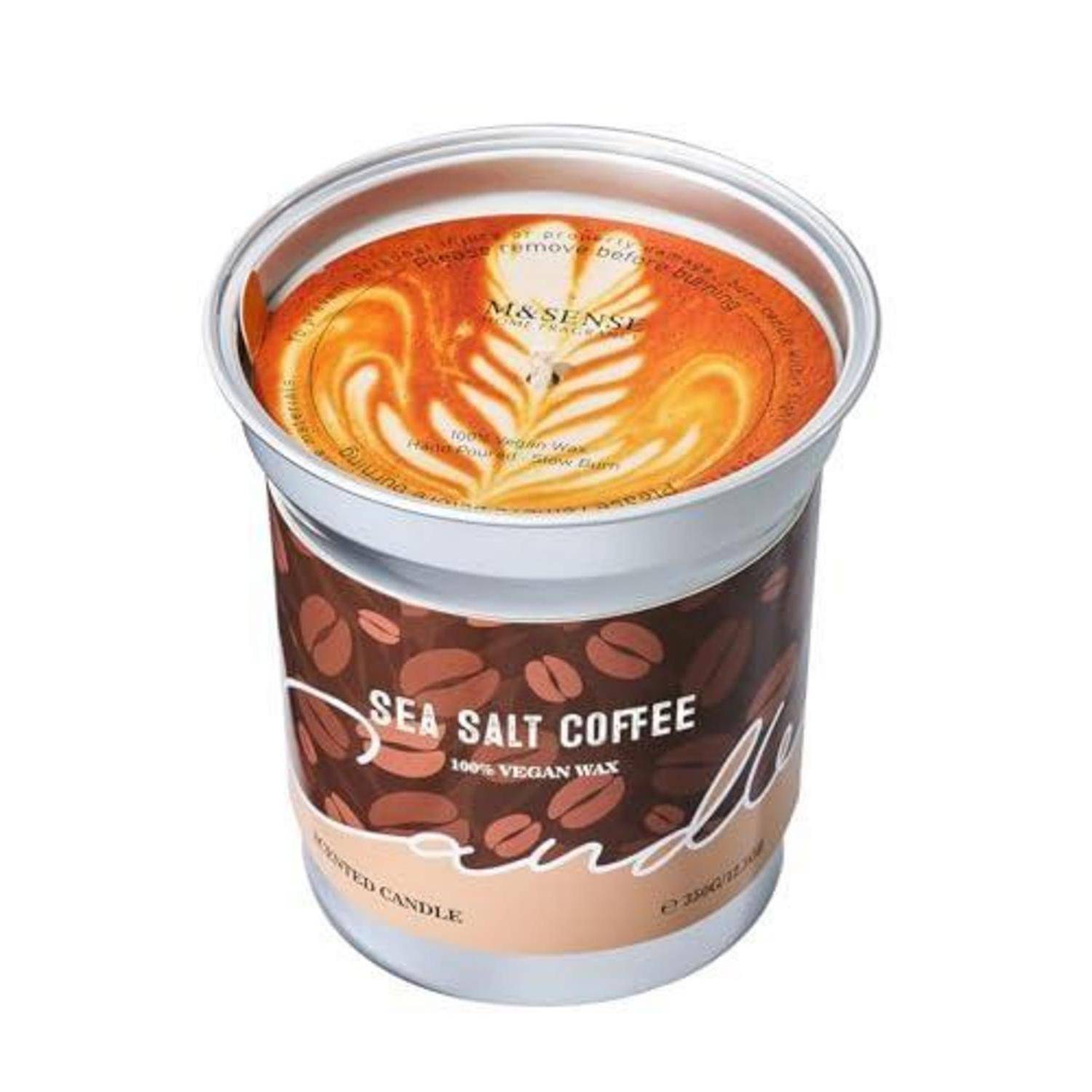 Meersalz-Kaffee-Duftkerze in einer Metalldose mit Kaffeebohnen-Etikett und orangefarbener Wachsoberfläche, die Latte-Art ähnelt.
