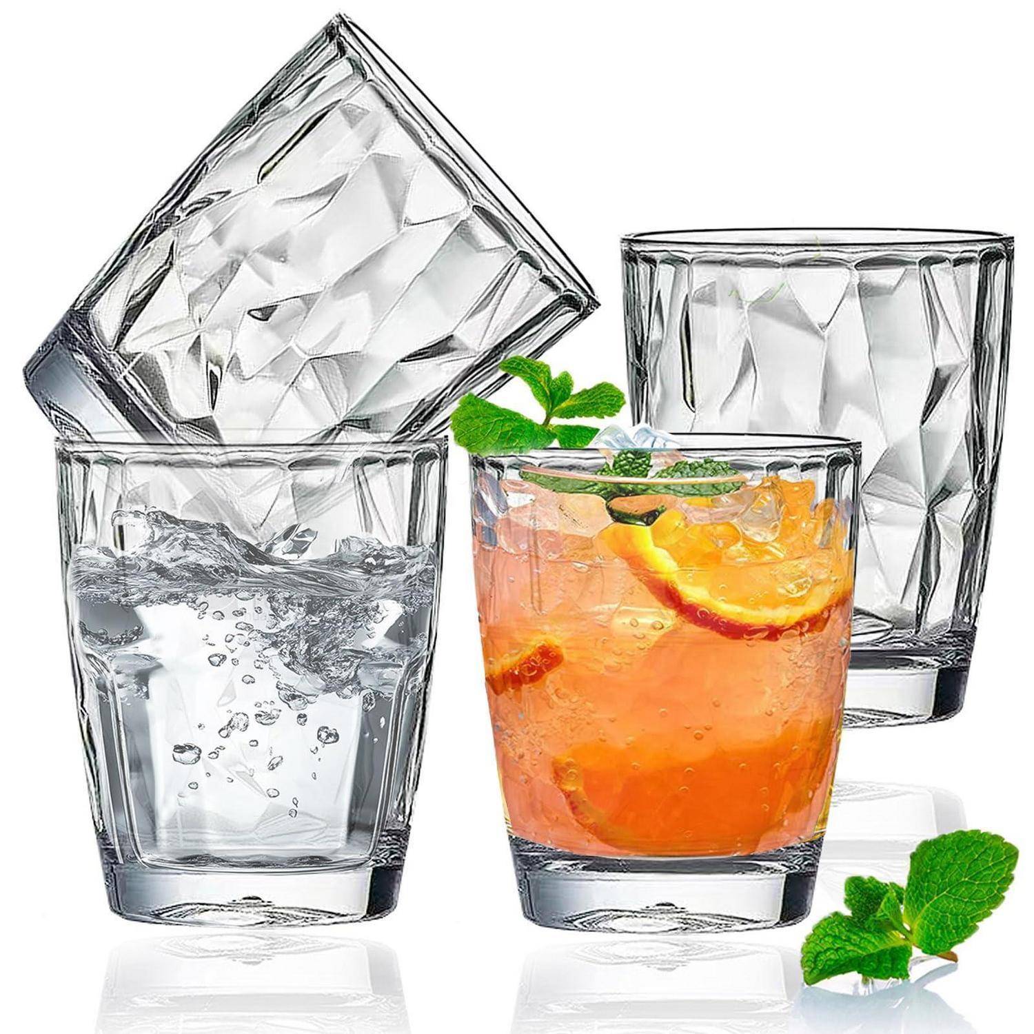 Satz aus vier facettierten klaren Trinkgläsern, eines gefüllt mit Wasser und eines mit Orangengetränk und Minze, auf weißem Hintergrund.