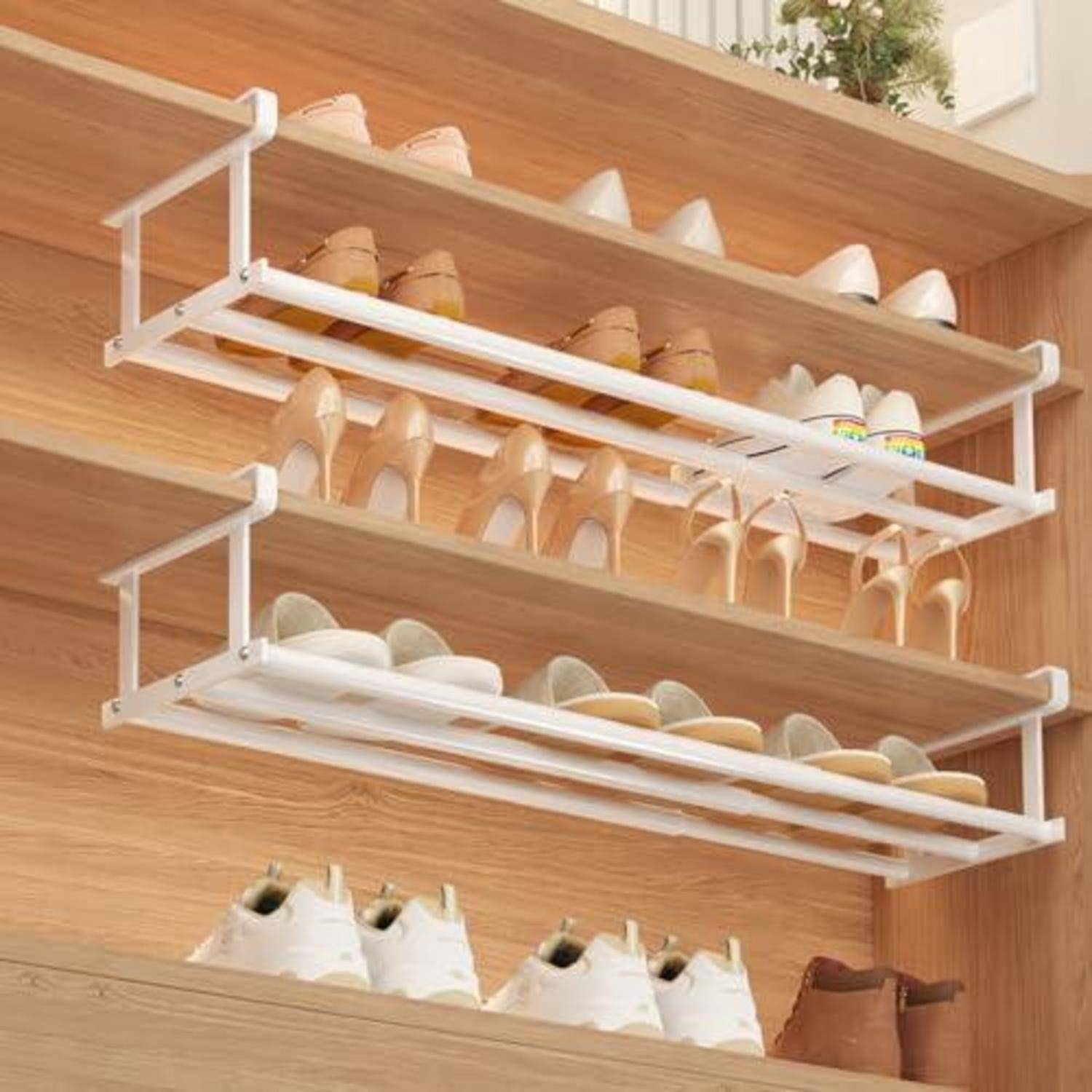 Drei an der Wand montierte Schuhregal in einem Holzschrank halten Reihen von hochhackigen Schuhen und Turnschuhen und organisieren Schuhwerk nach Regalboden.