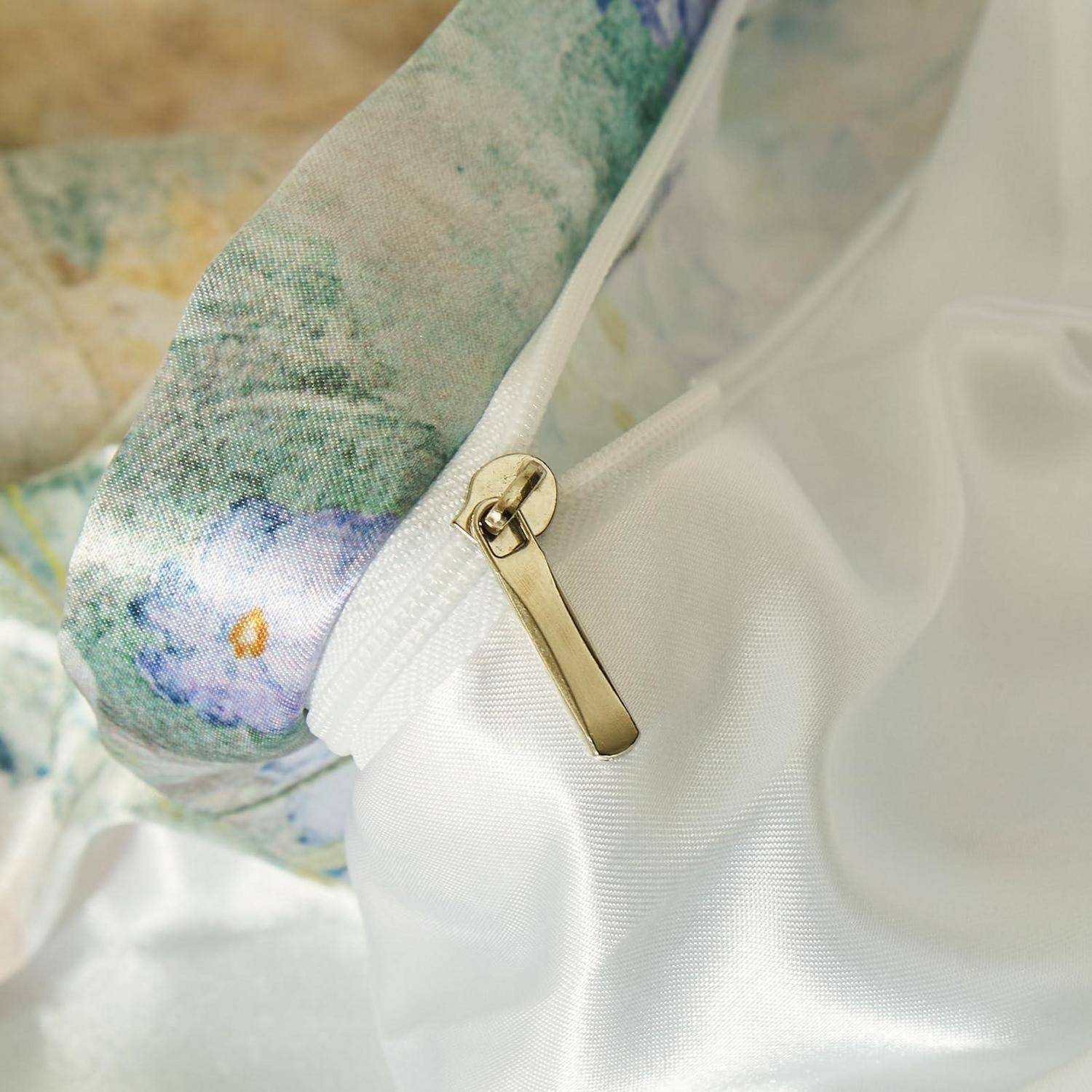 Nahaufnahme einer weißen Satintasche oder eines Kissens mit Reißverschluss, mit einer Stoffkante im Blumenmuster und goldfarbenem Reißverschlussschieber.