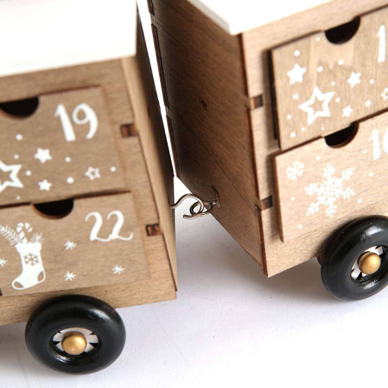 Holzadventskalender-Schubladen auf schwarzen Rollen, mit nummerierten Fächern und weihnachtlichen Stern- und Schneeflocken-Dekorationen, die nebeneinander verbunden sind.